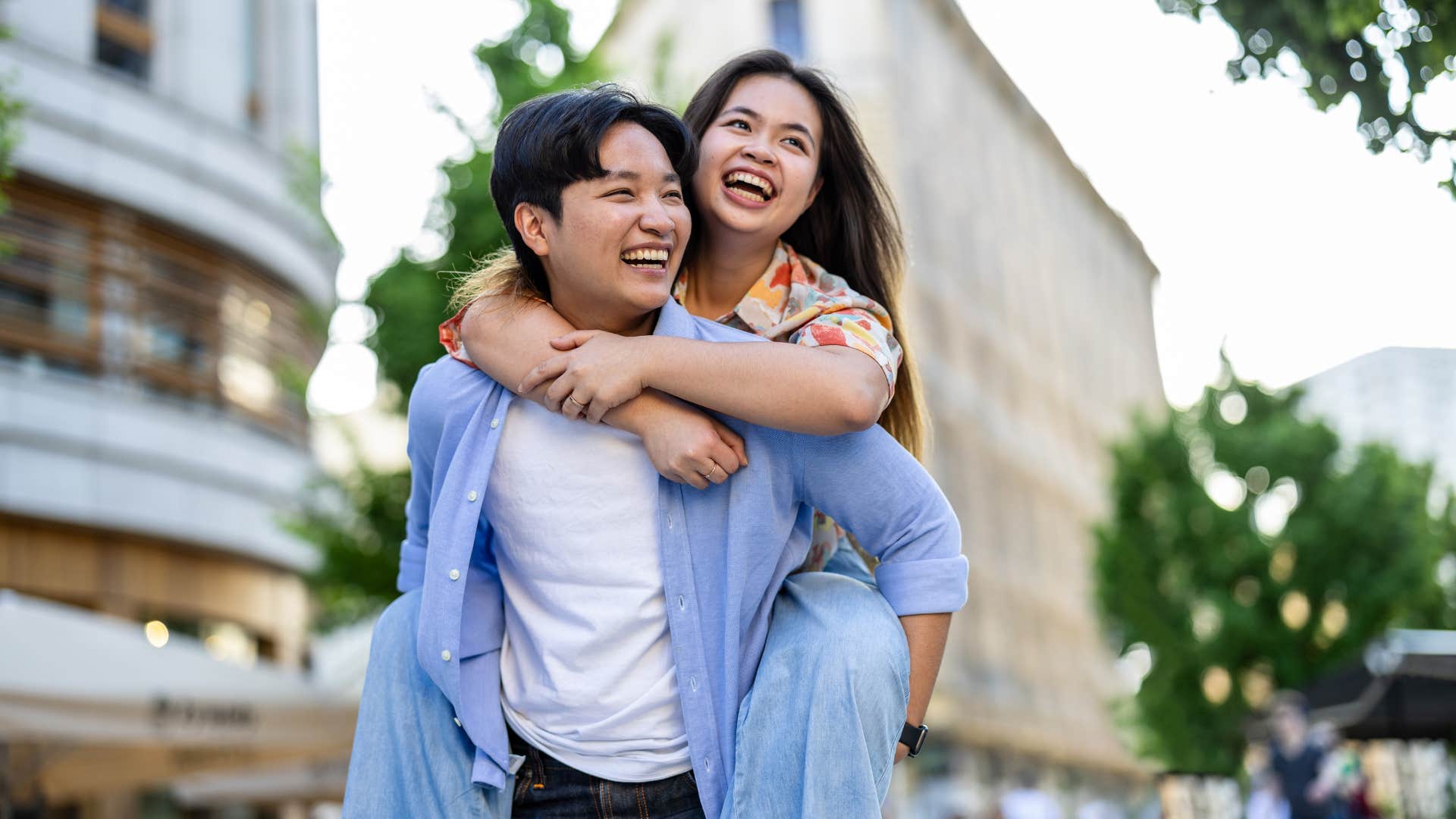 man in blue jacket giving woman piggy back ride as she feels energized with him