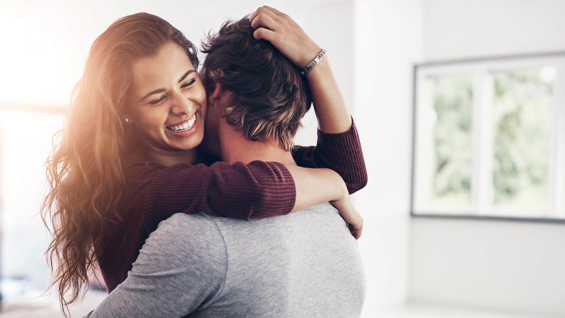 couple laughing around each other a lot as they hug and woman in red smiles