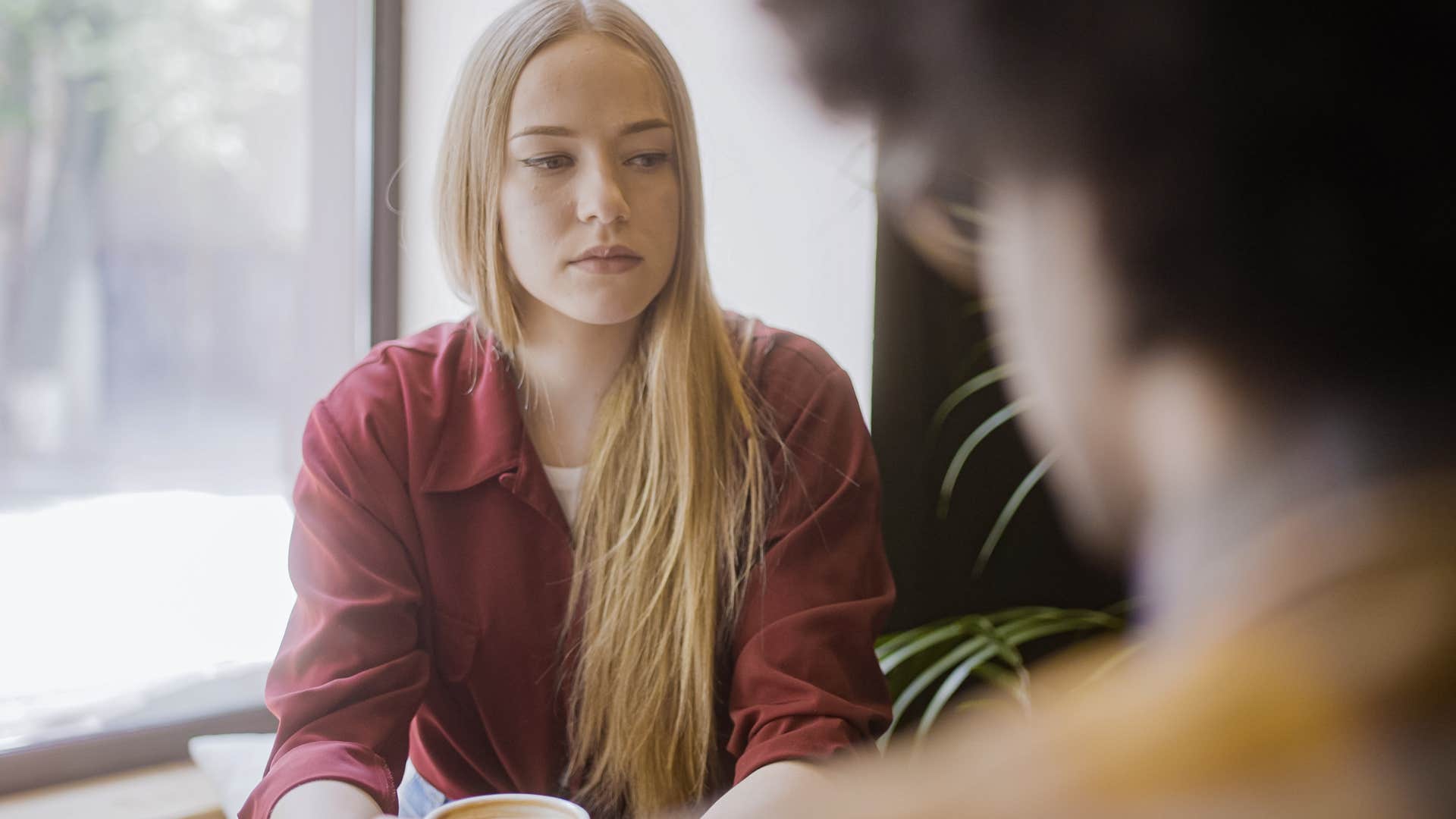 woman who fears being excluded talking to her friend in a coffee shop