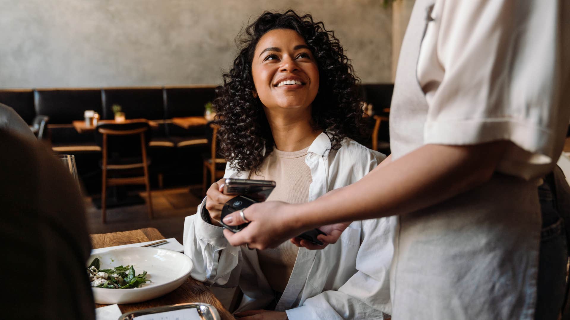 woman worried about tipping paying at a restaurant