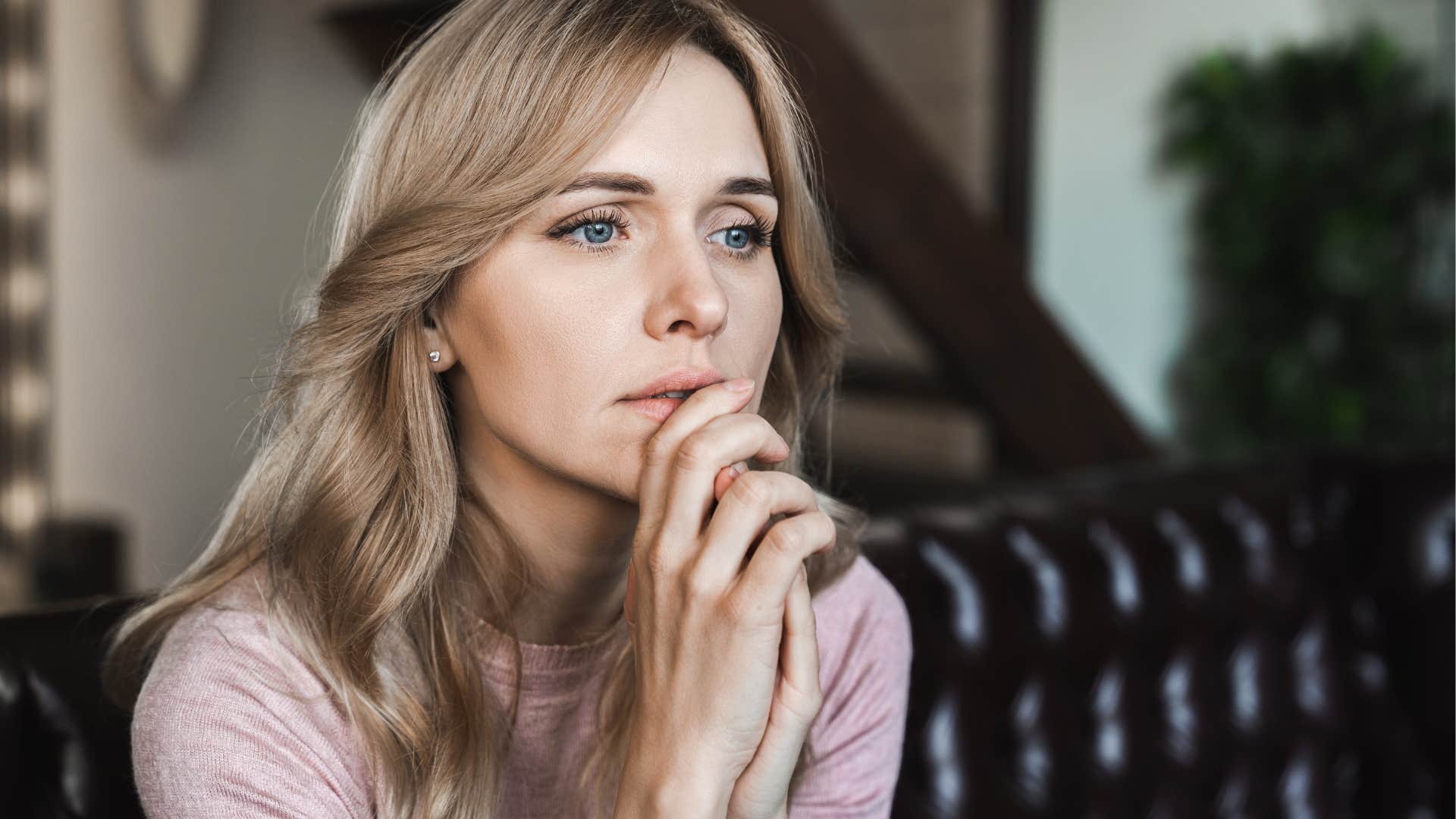 Woman who can't afford to live alone sitting on her couch.
