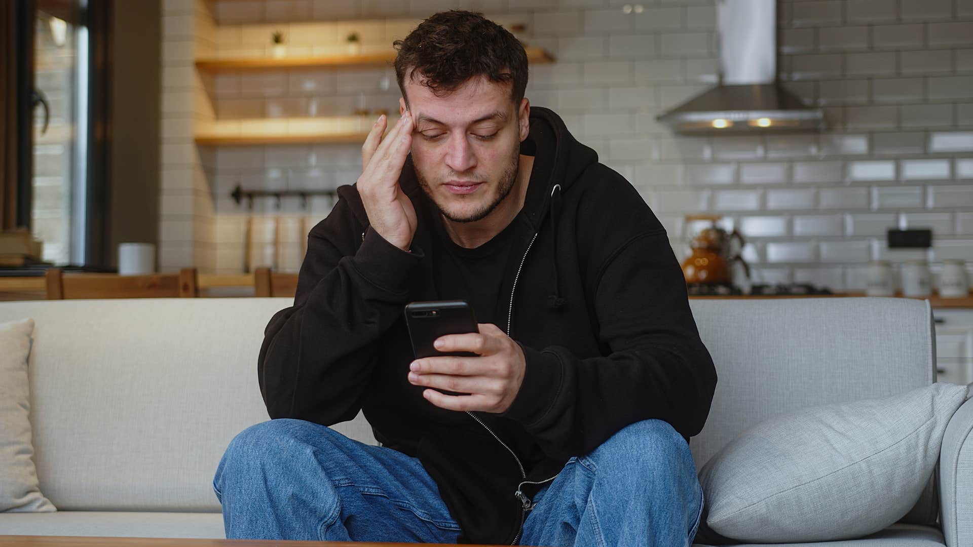 Man who's too plugged into the news sadly scrolling on his phone.