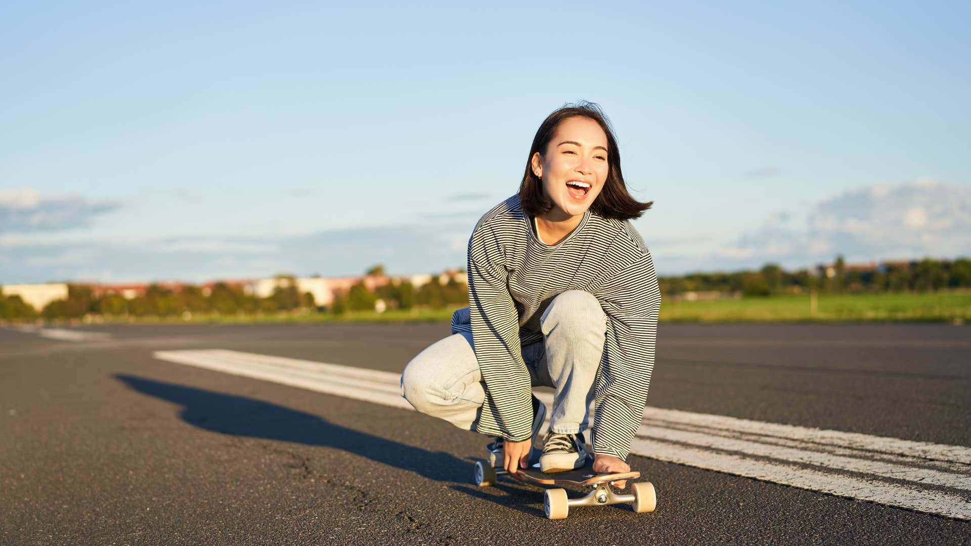 a gen x teen rides her skateboard dangerously down a road