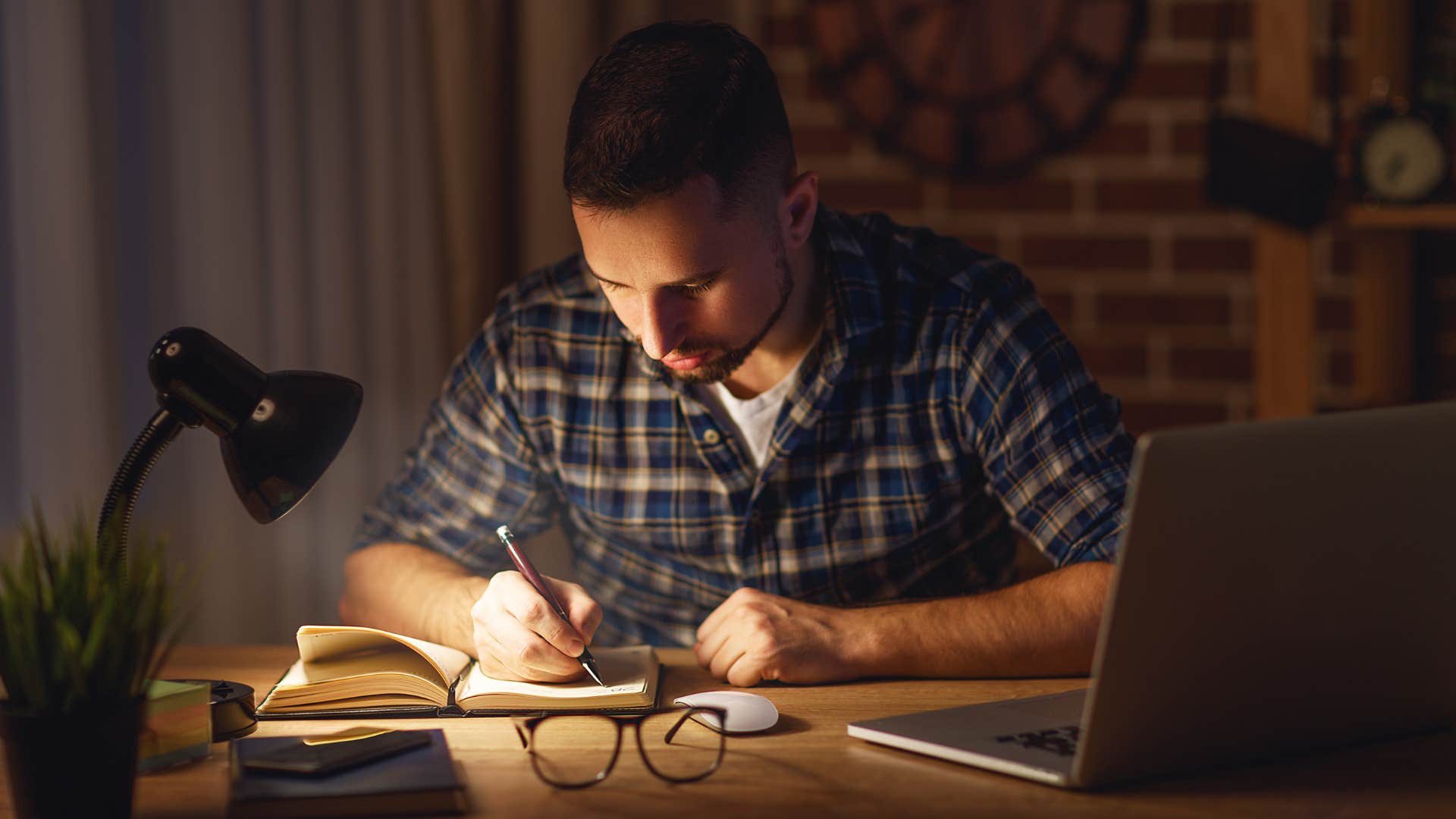 creative man writing in journal at night