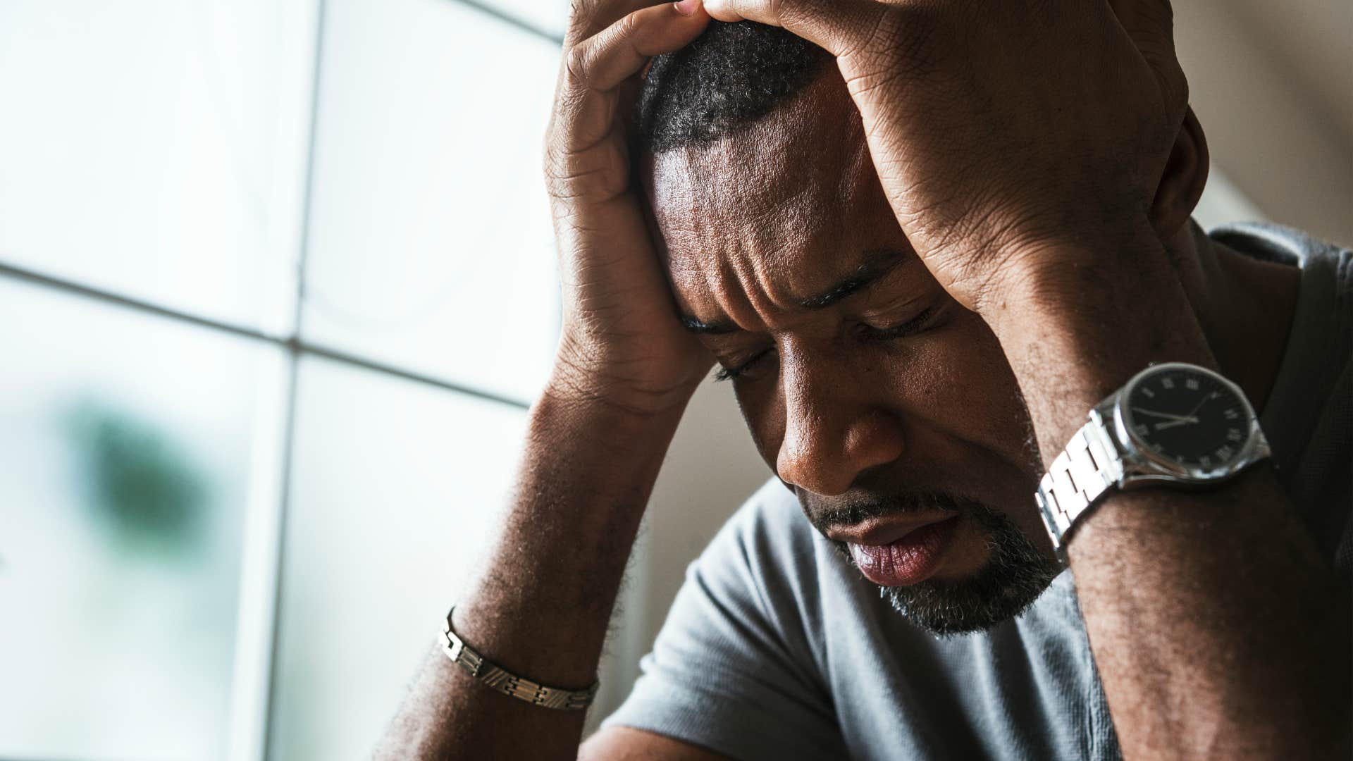 Man who's stuck in patterns of toxic behavior holding his head.