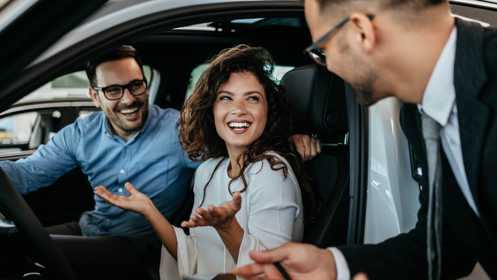 a salesman helps a woman pick a car that is paid for by her family member