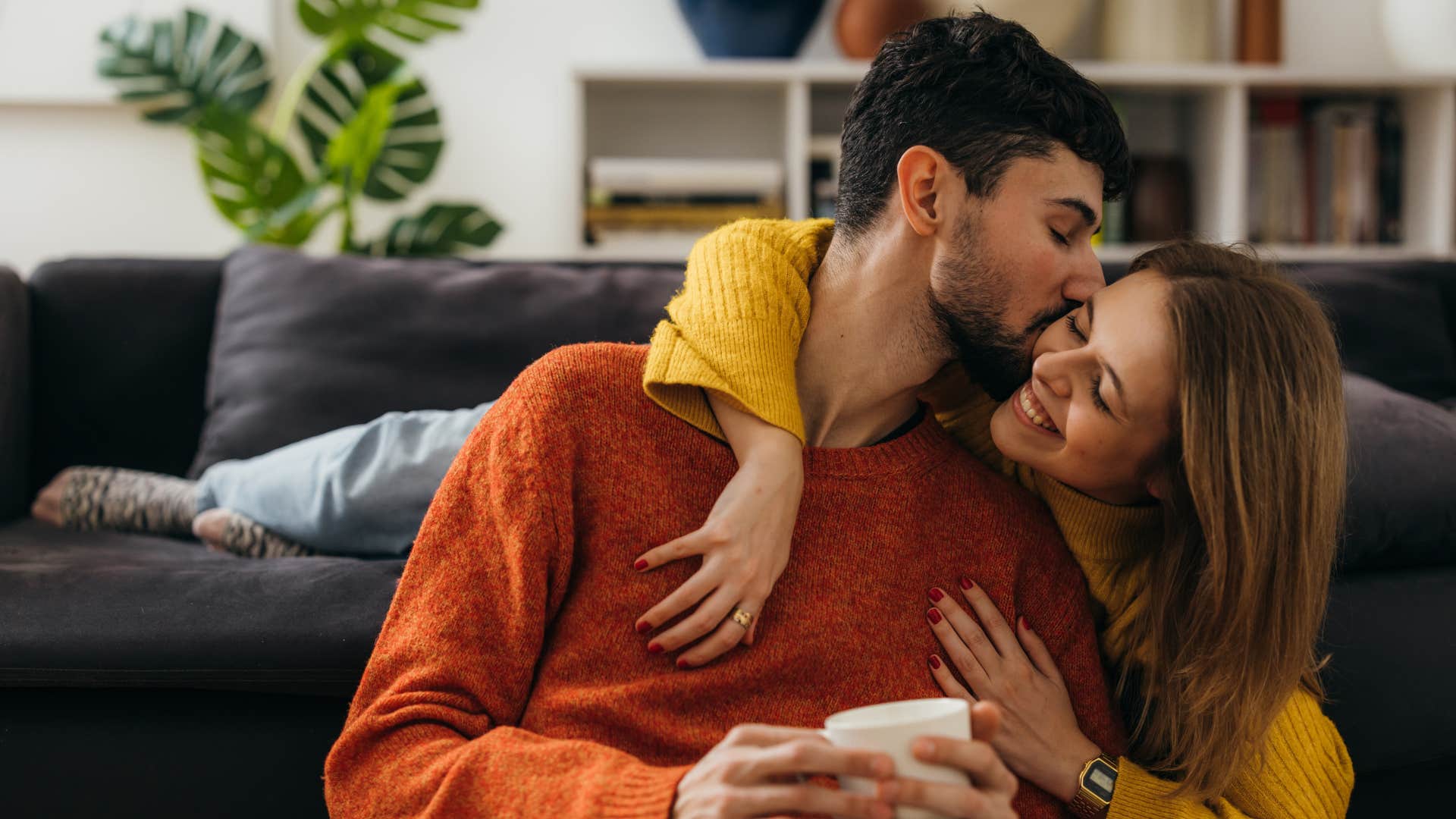 man in red shirt practicing gratitude as he kisses woman on the cheek in yellow shirt