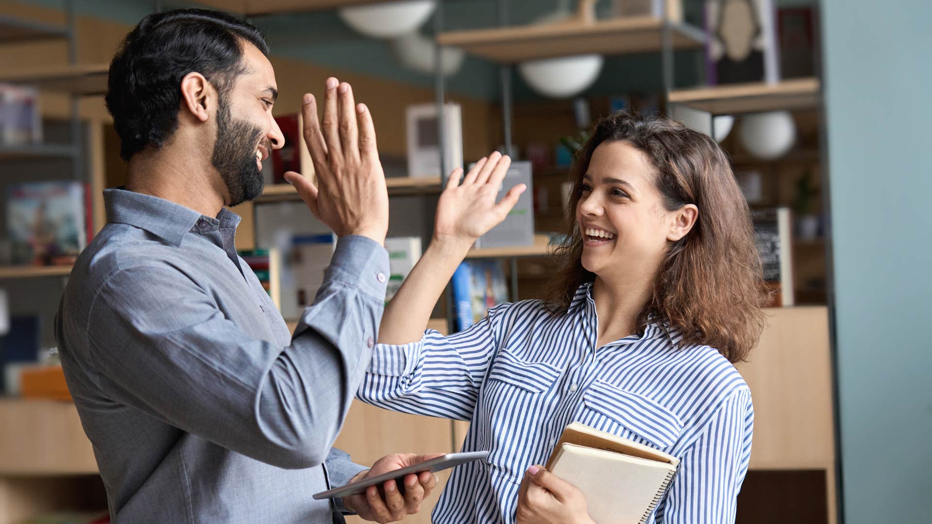 man and woman in blue high-fiving as man respects women