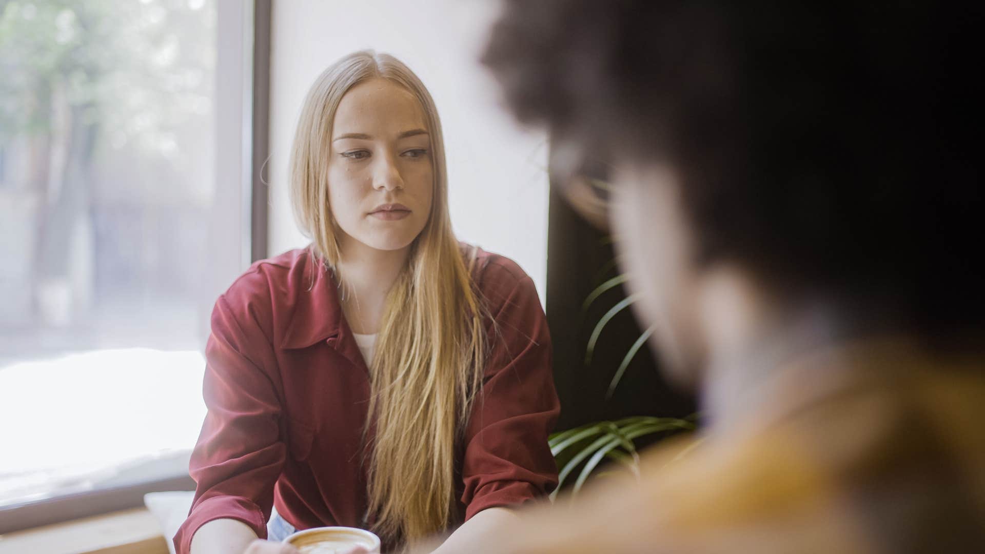 woman in red shirt looking upset as when she does talk to partner it's surface level