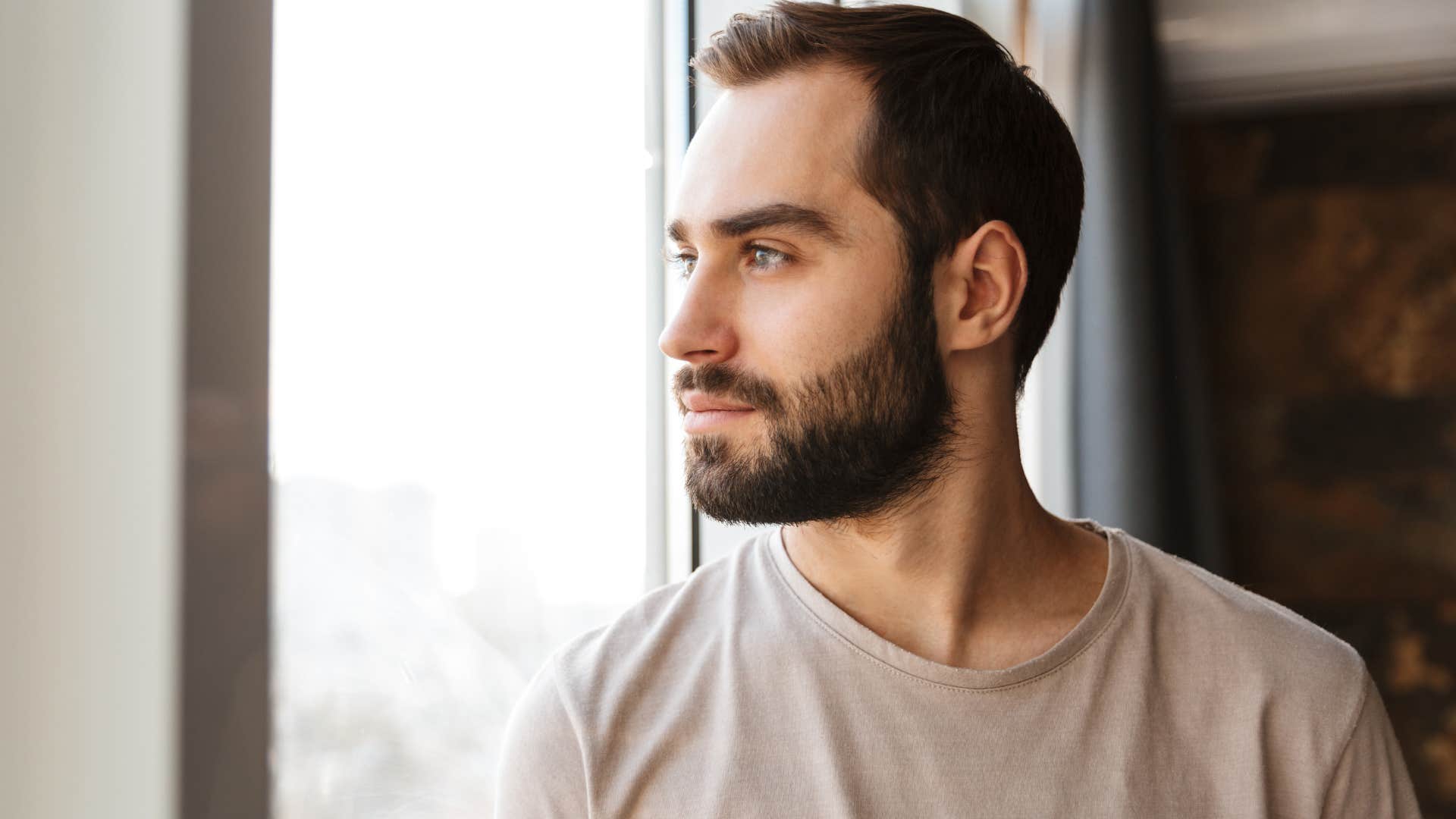 Man who struggles with independence looking out a window.