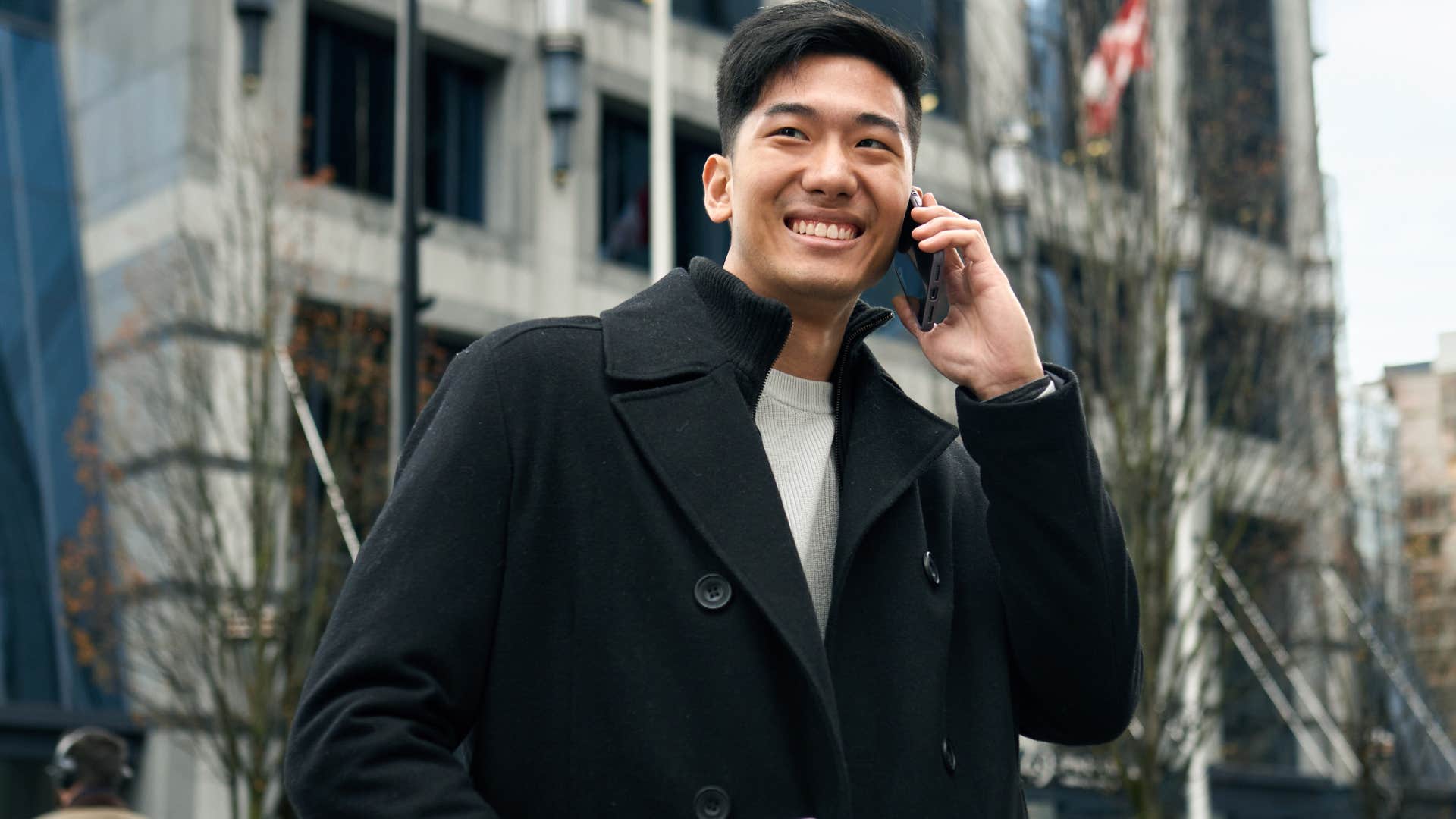 man with a confident walk smiling while on the phone