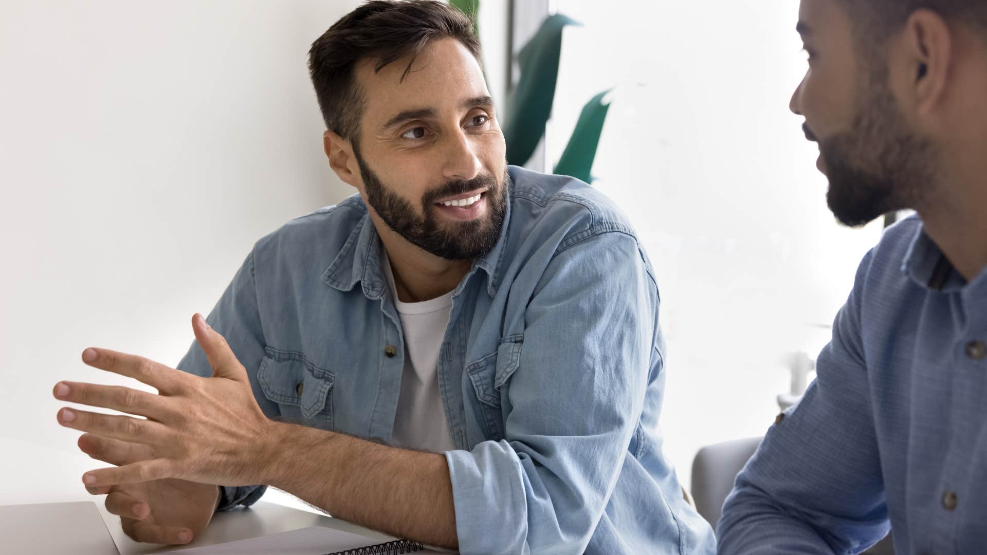 man smiling and leaning into conversation with co-worker