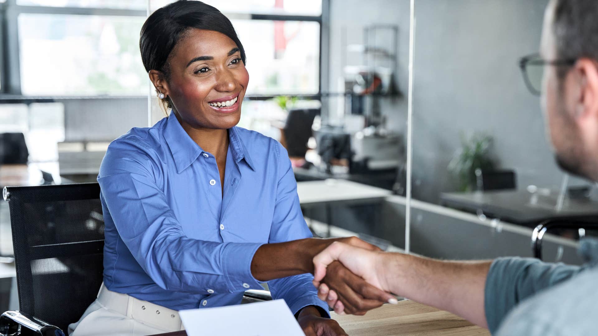 woman intentionally smiling and shaking co-worker's hand