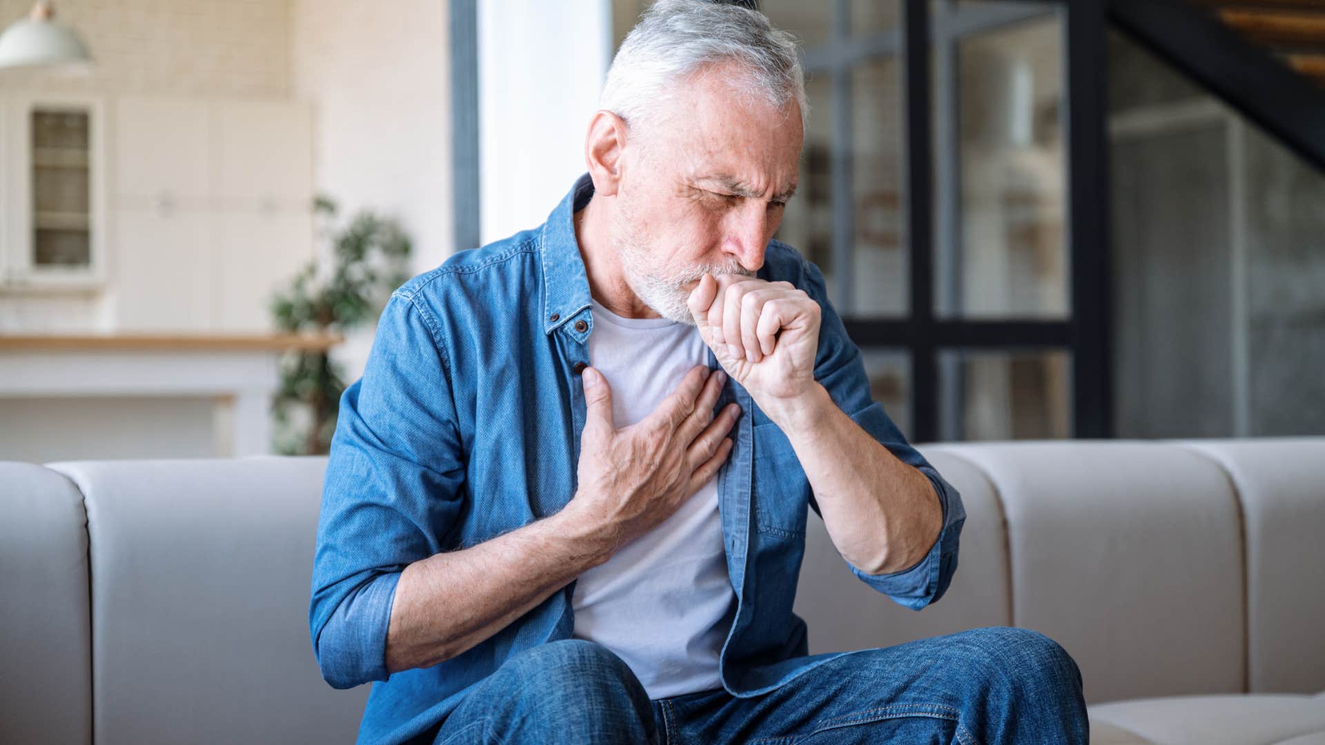 man in constant pain coughing holding his chest