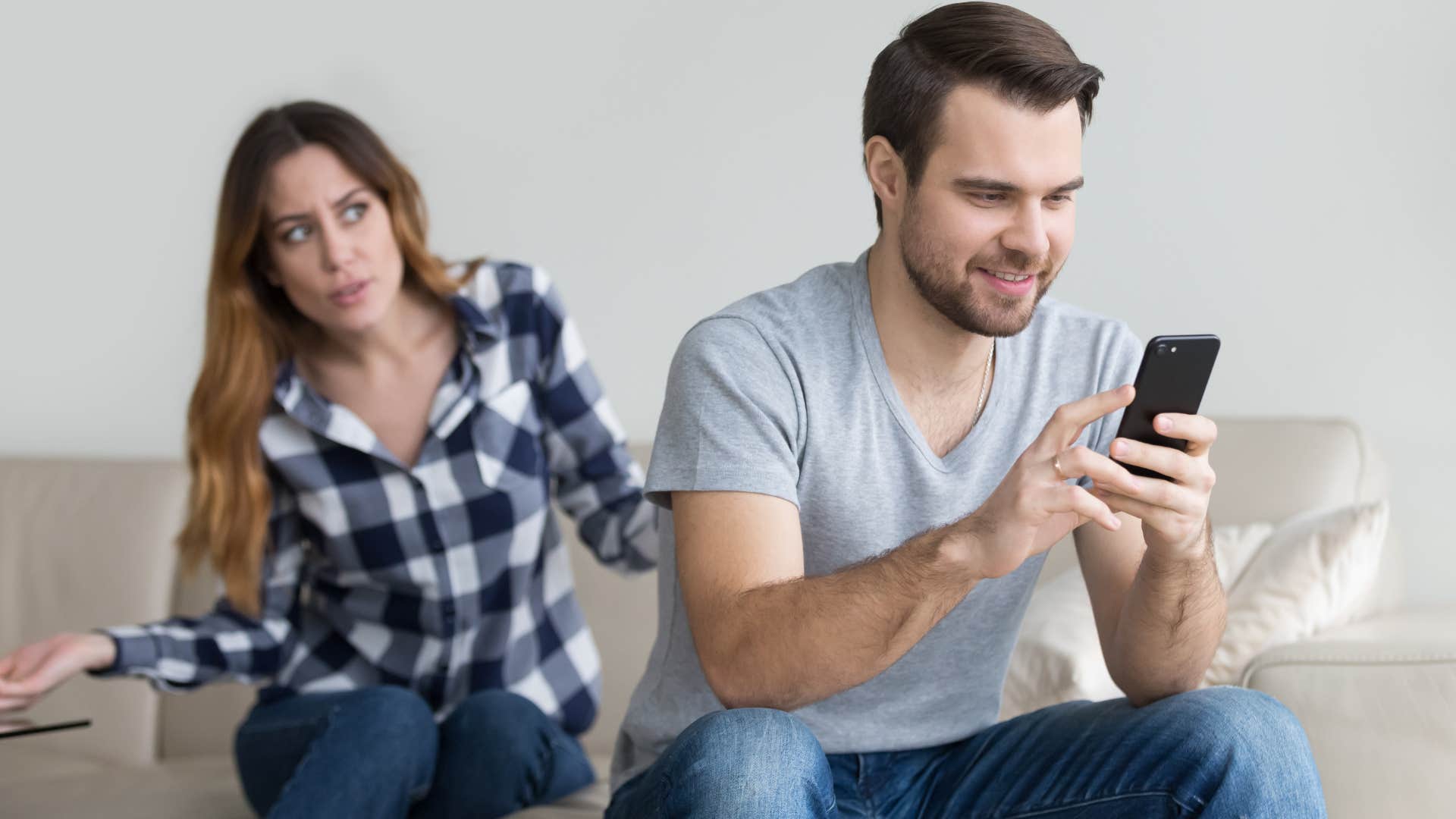 man fidgeting with his phone during conversation with his girlfriend