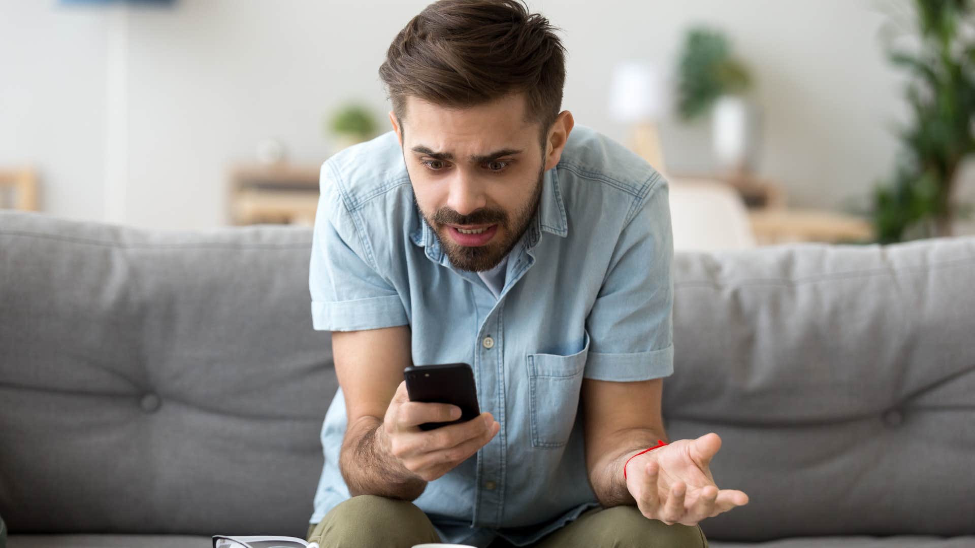 Man looking at a text on his phone that excludes them from plans.