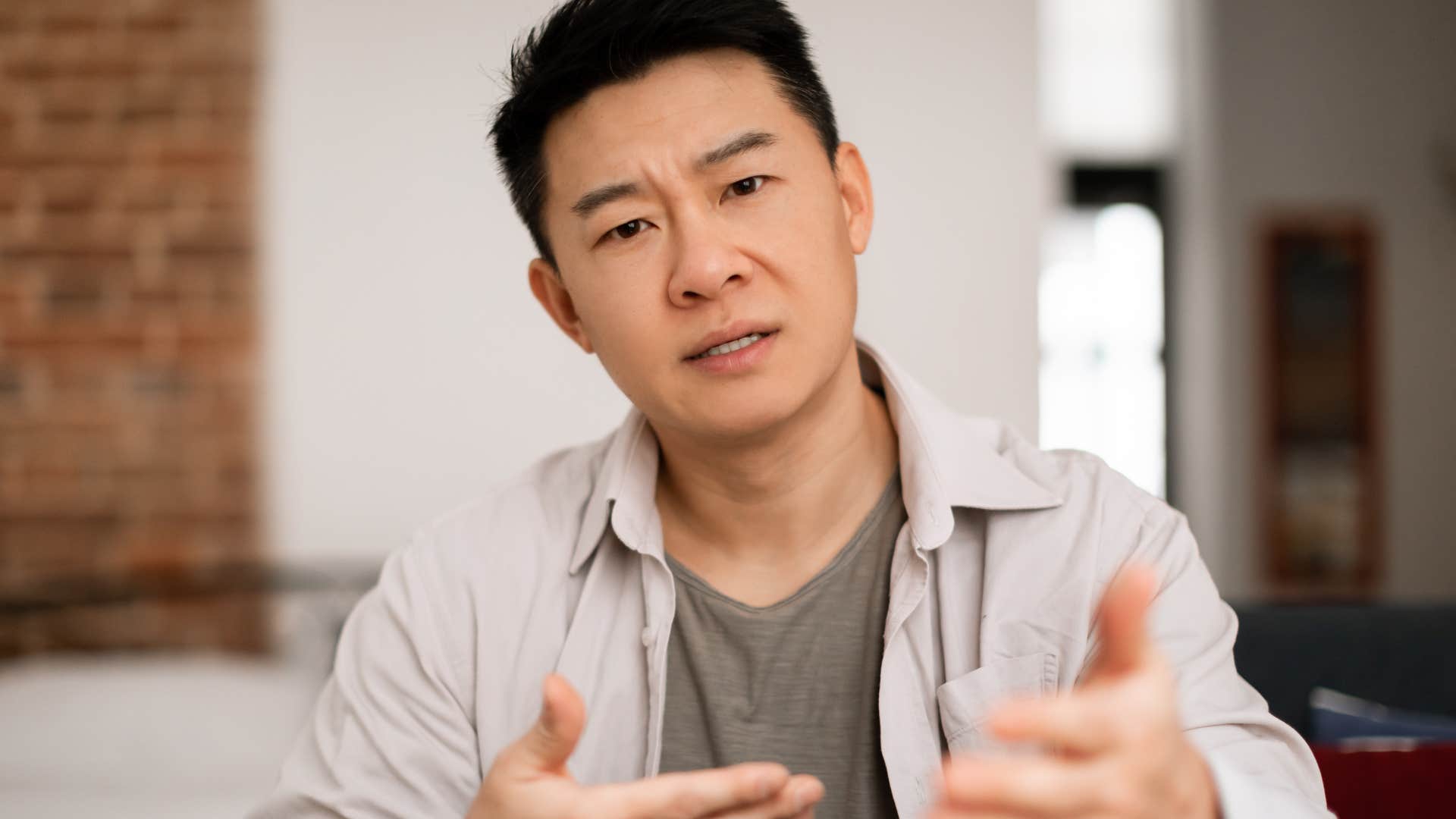 Man who can twist their words talking to someone behind the camera.