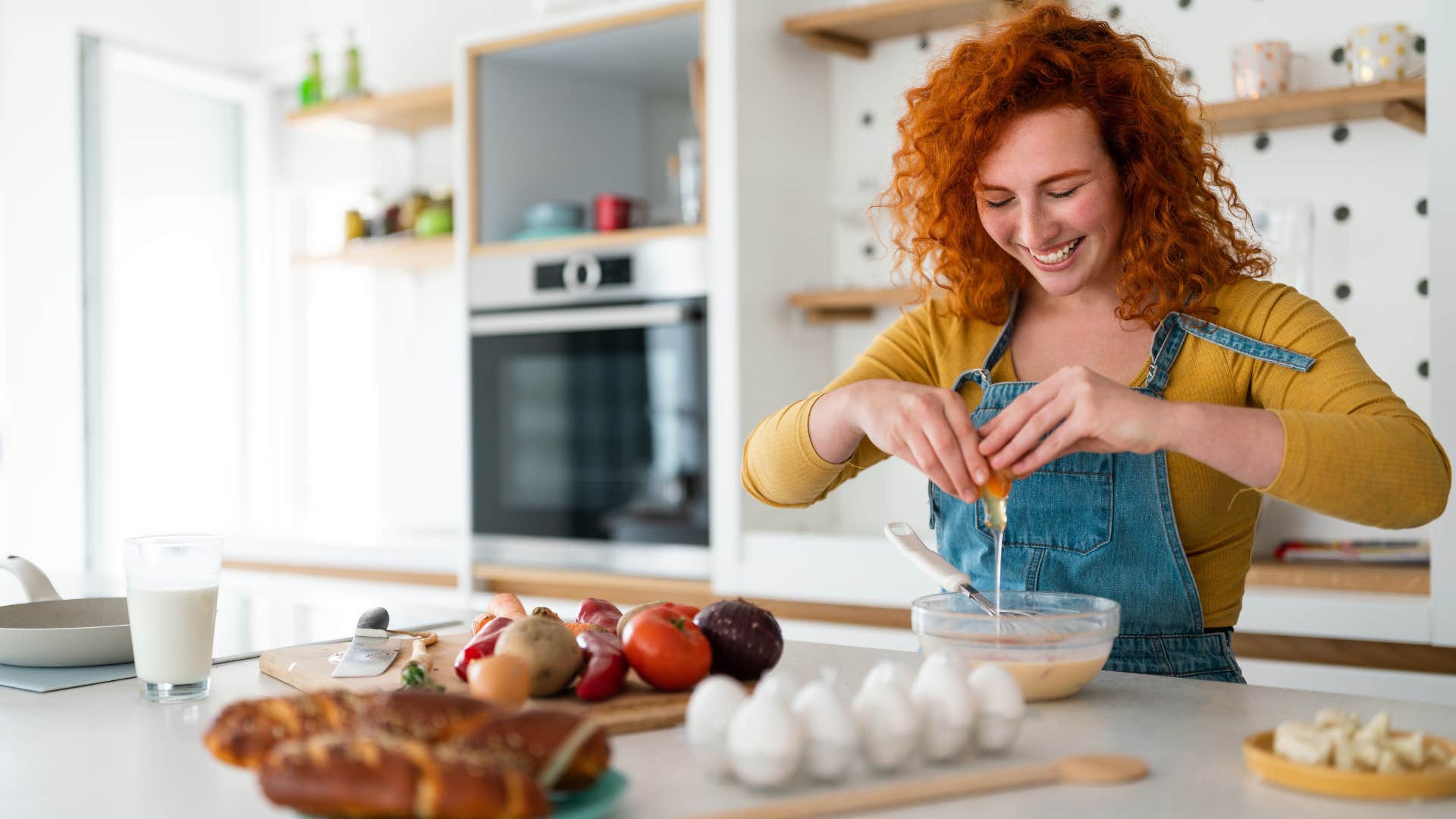 woman cracking eggs to make breakfast