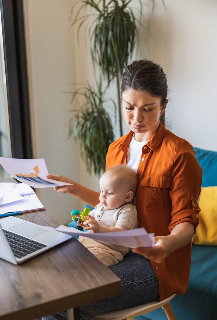 mom holding baby while working because she gets less than an hour of time to herself a day