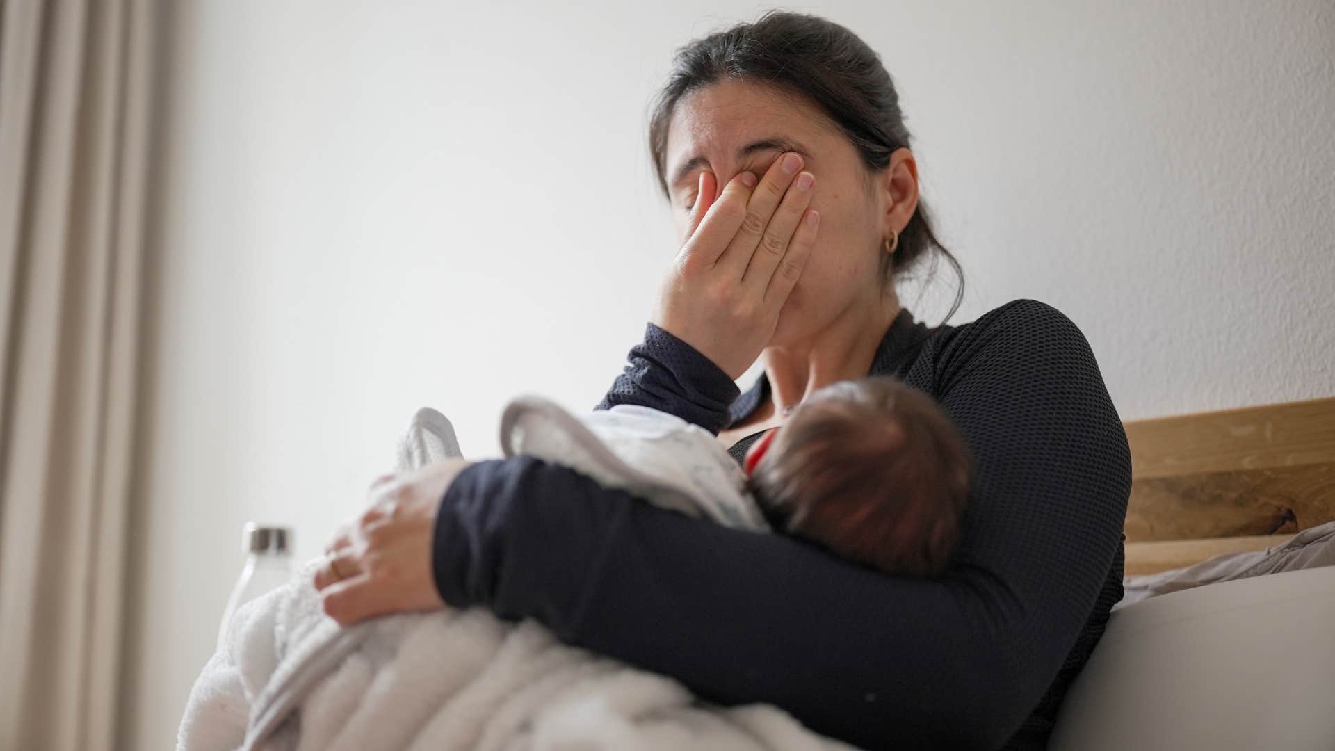 woman feeling ashamed for nursing in public as she forces herself to nurse in her bedroom