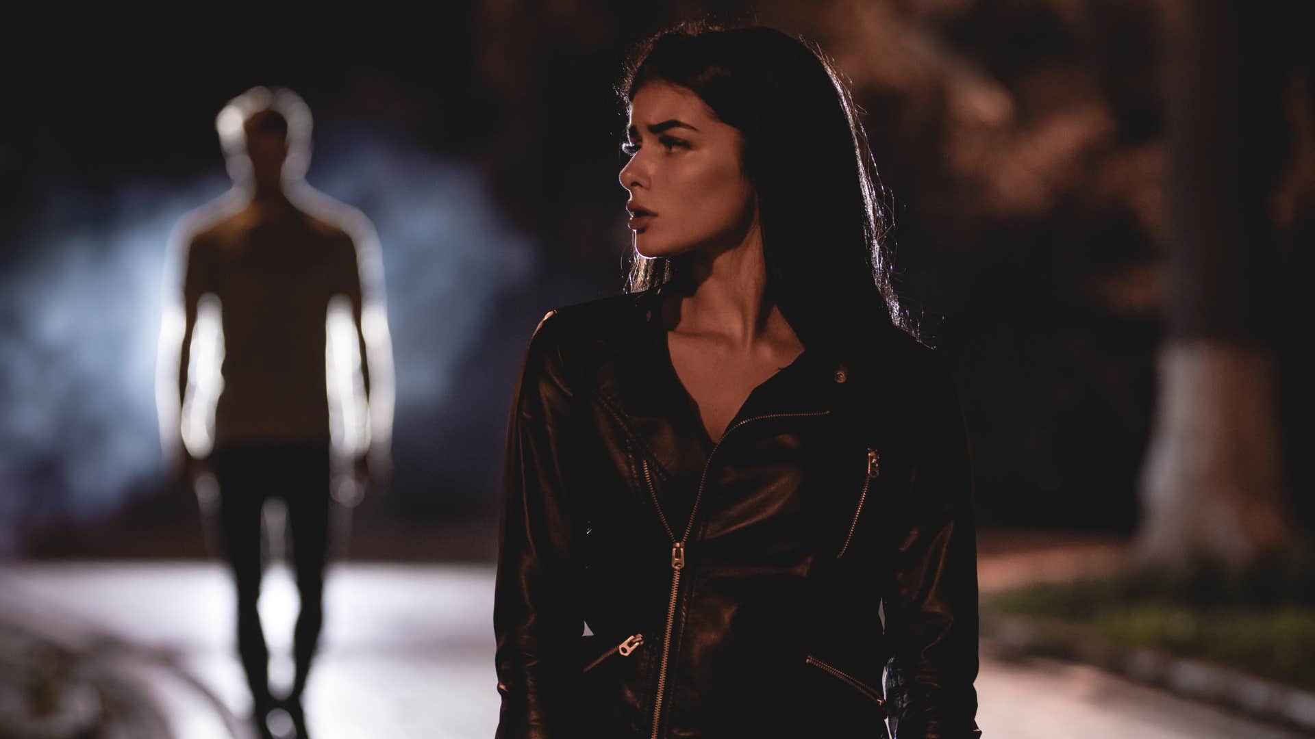 woman walking outside after dark as a man follows her