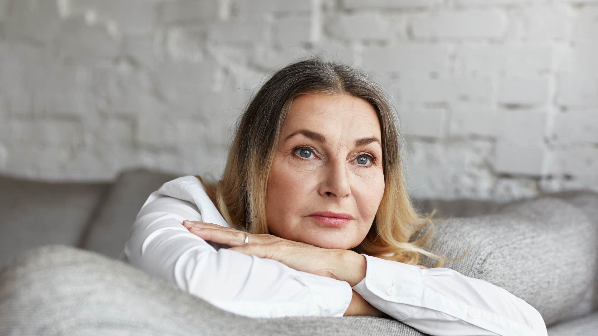 older woman sitting on couch looking out