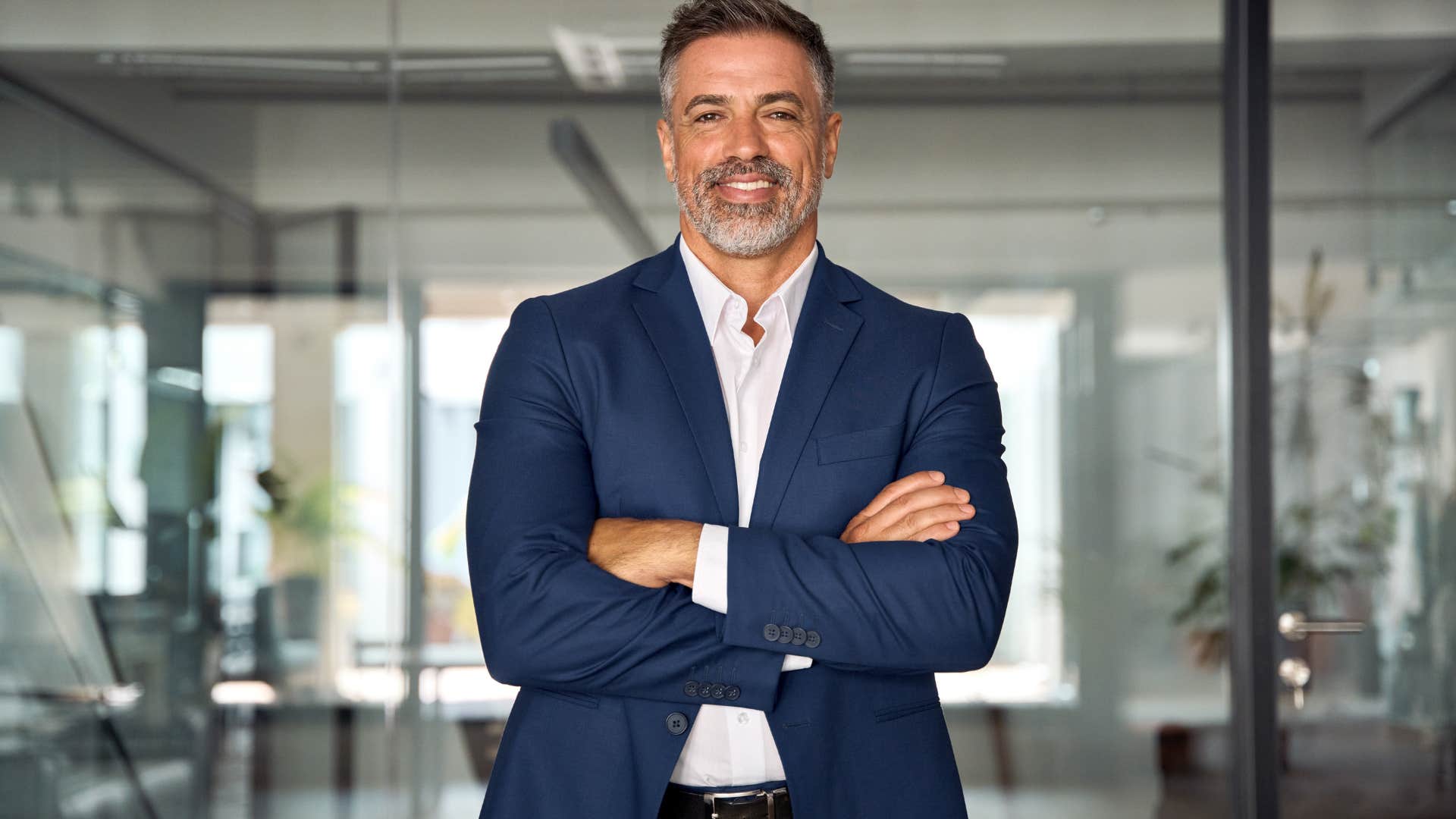 older businessman standing with arms crossed in office