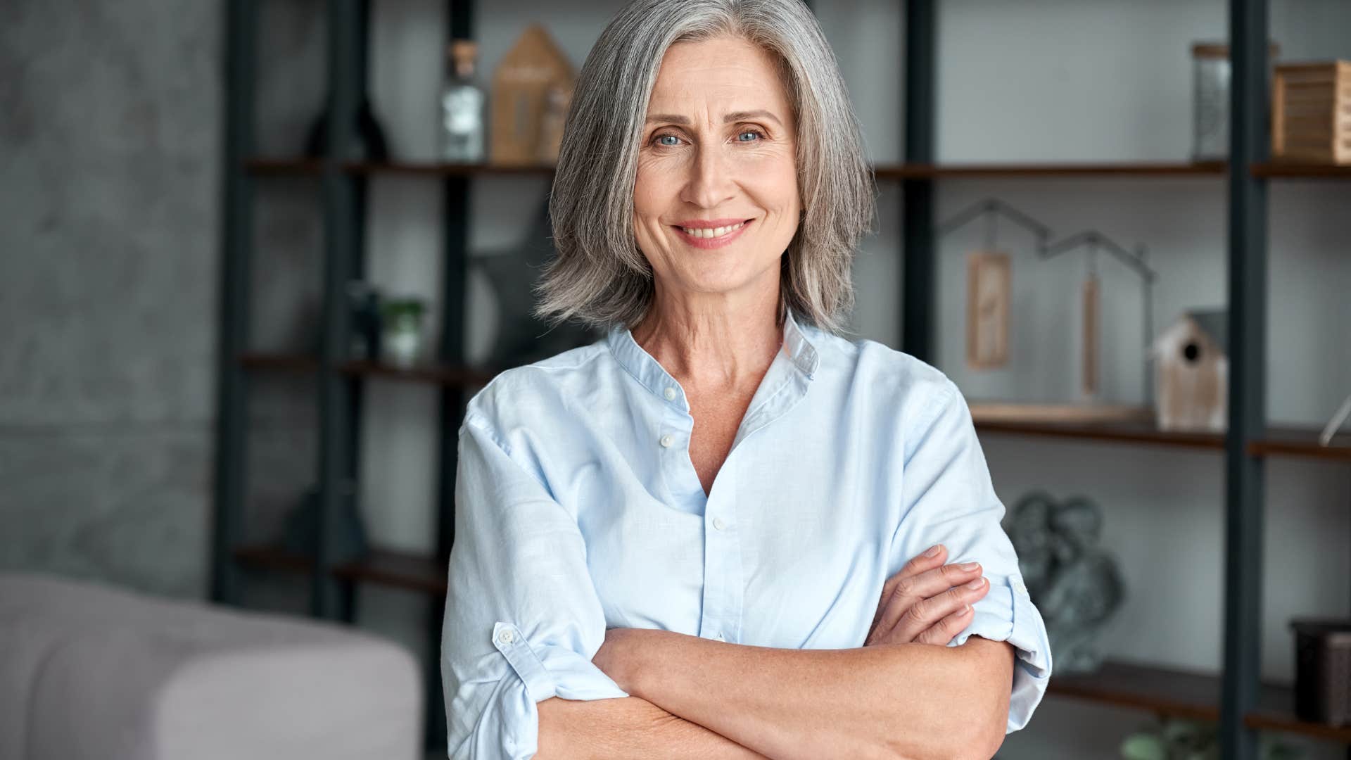 older businesswoman standing with arms crossed in office