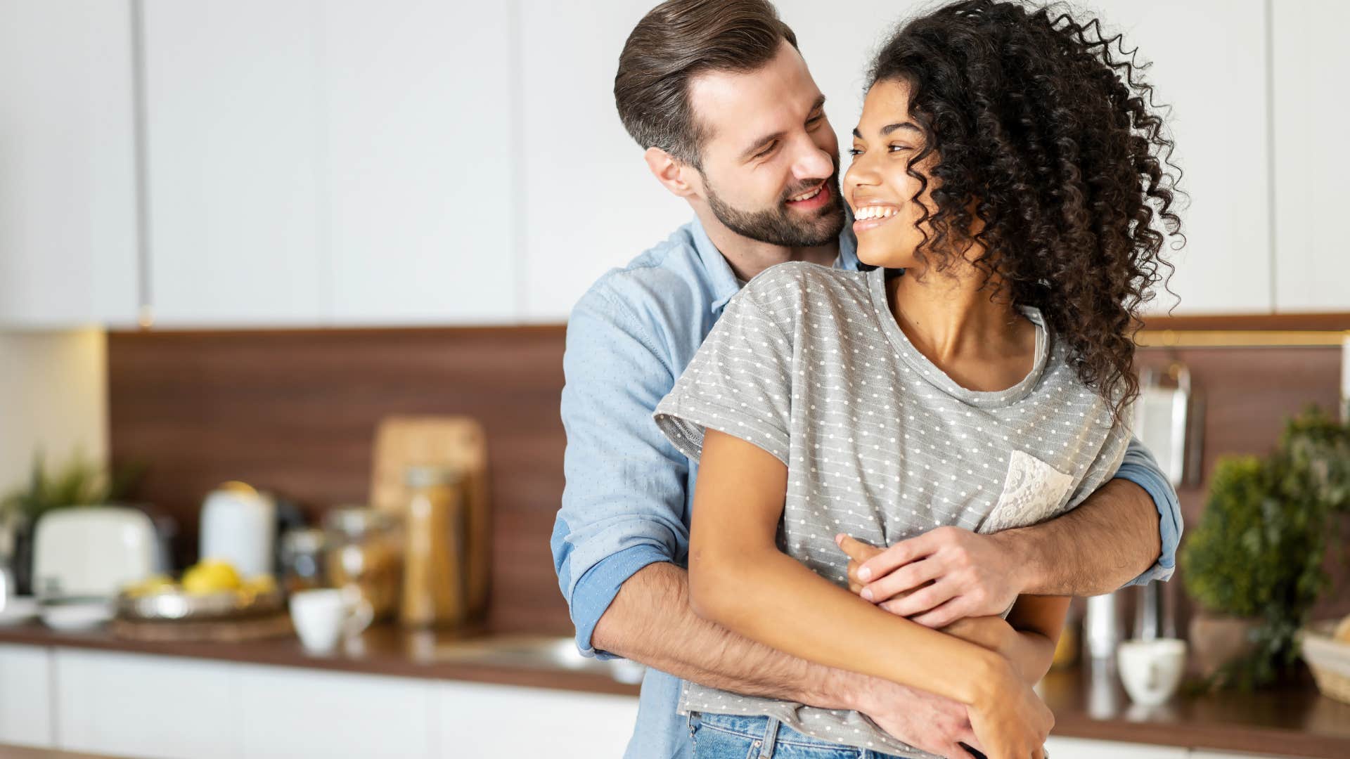 couple cuddling together in kitchen unafraid to express themselves