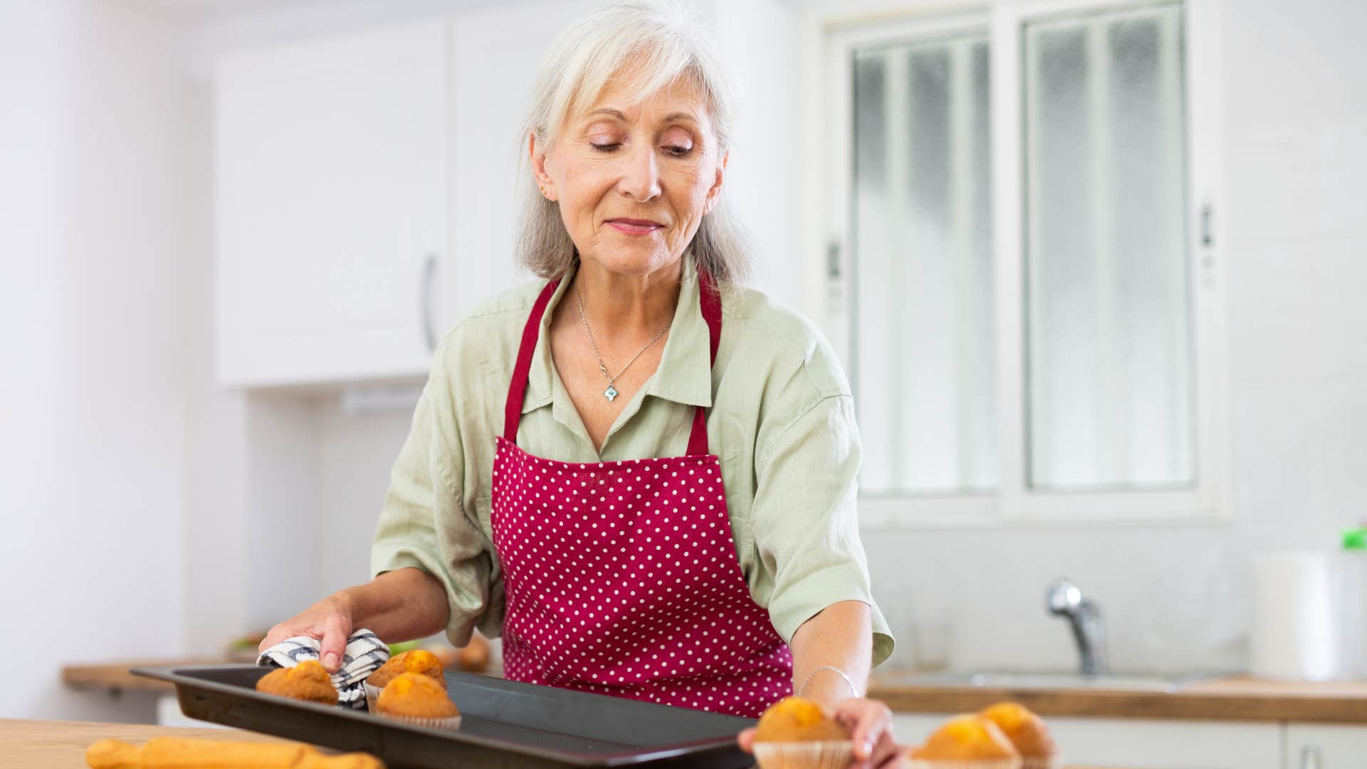 a boomer woman bakes muffins at home