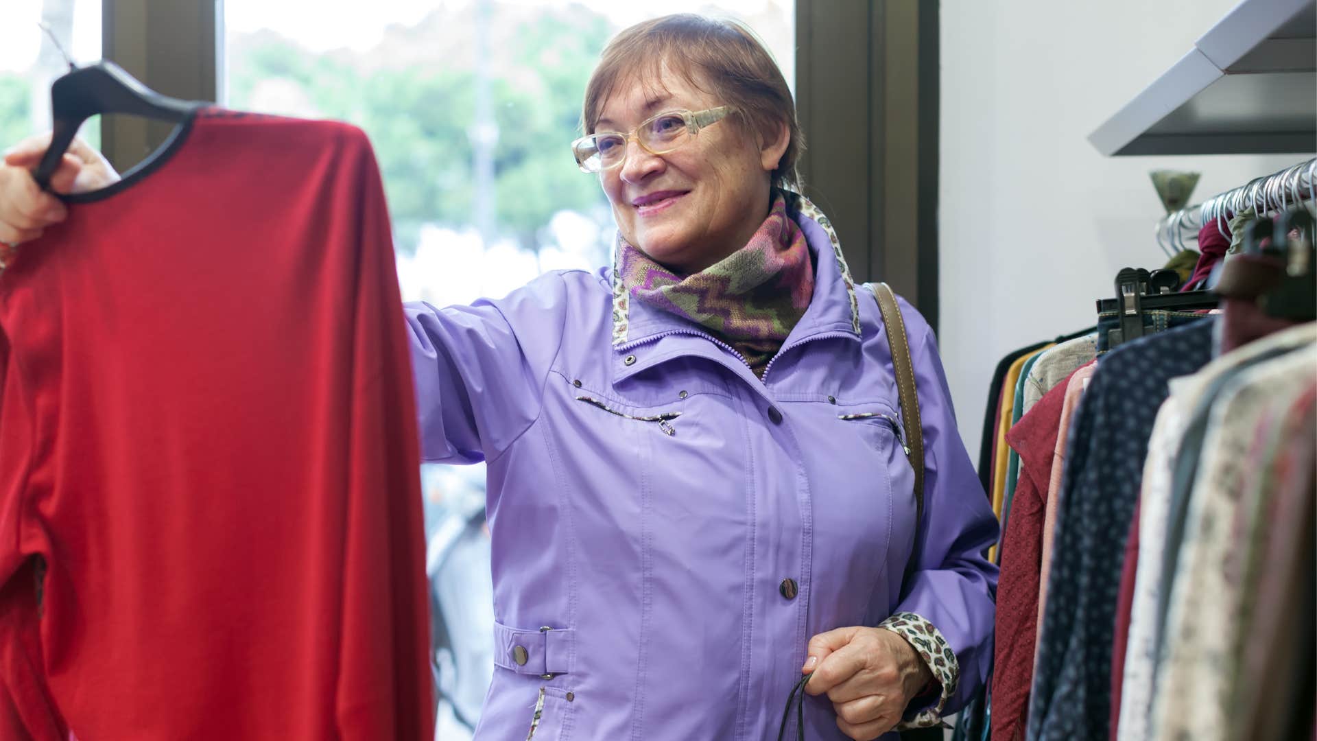 a boomer woman shops for secondhand clothes at a thrift store