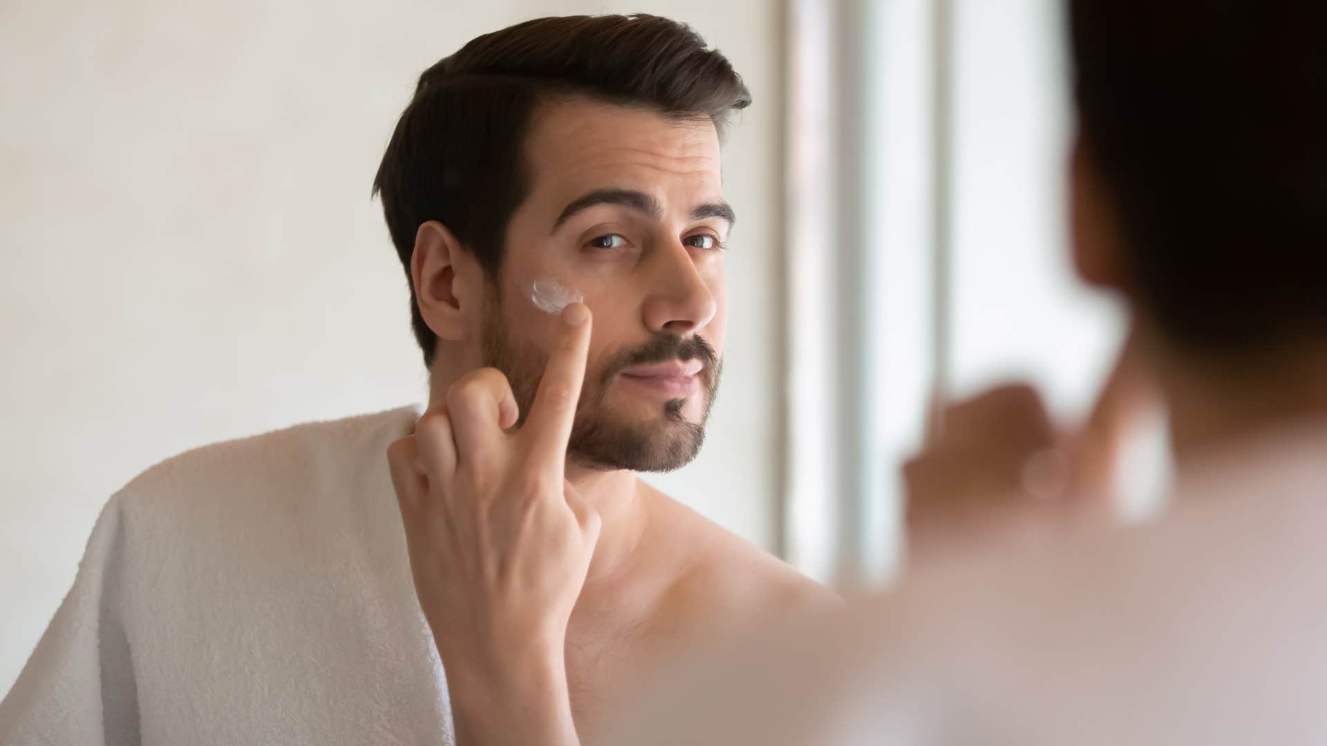 man putting on skincare products