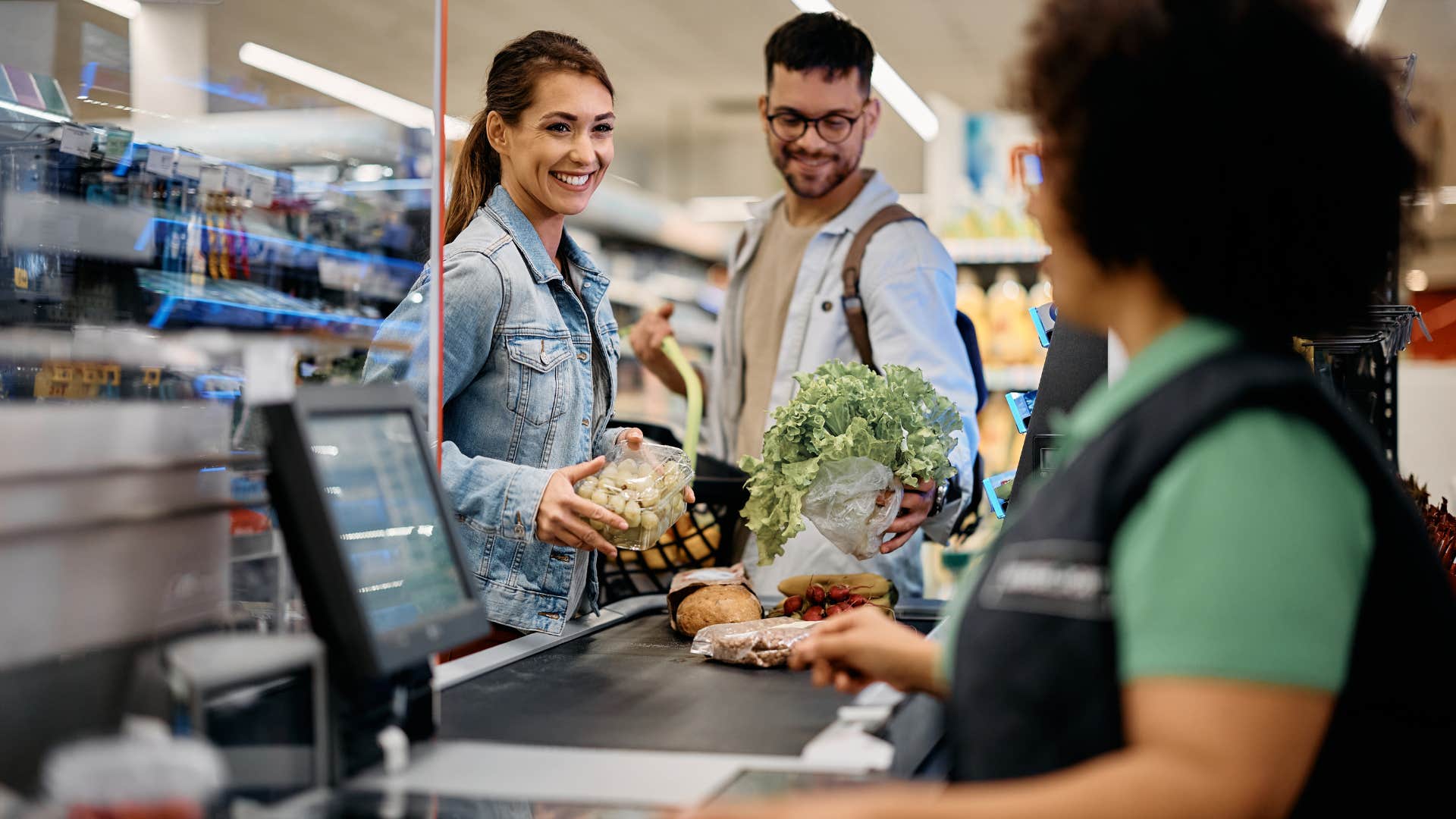 couple checking out at grocery store not using reusable bags