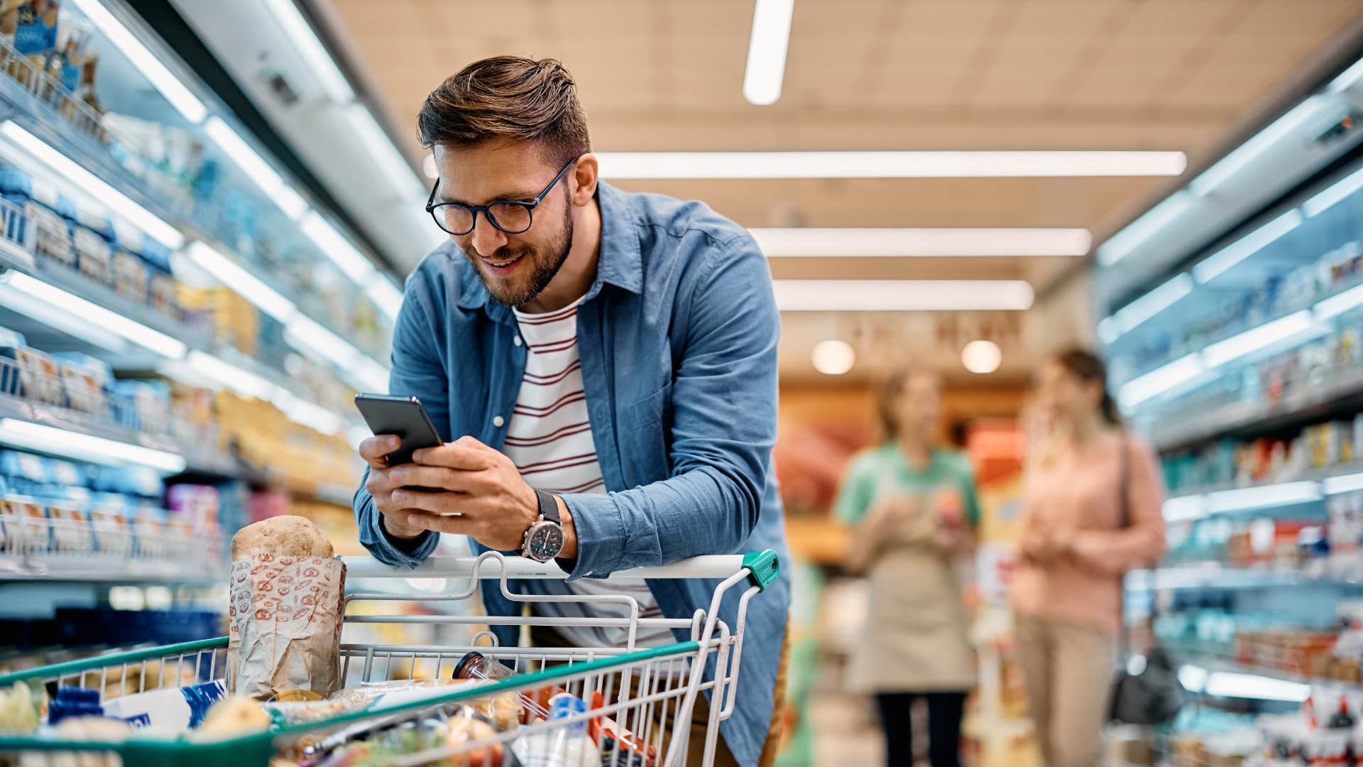 man looking at grocery list on his phone while shopping