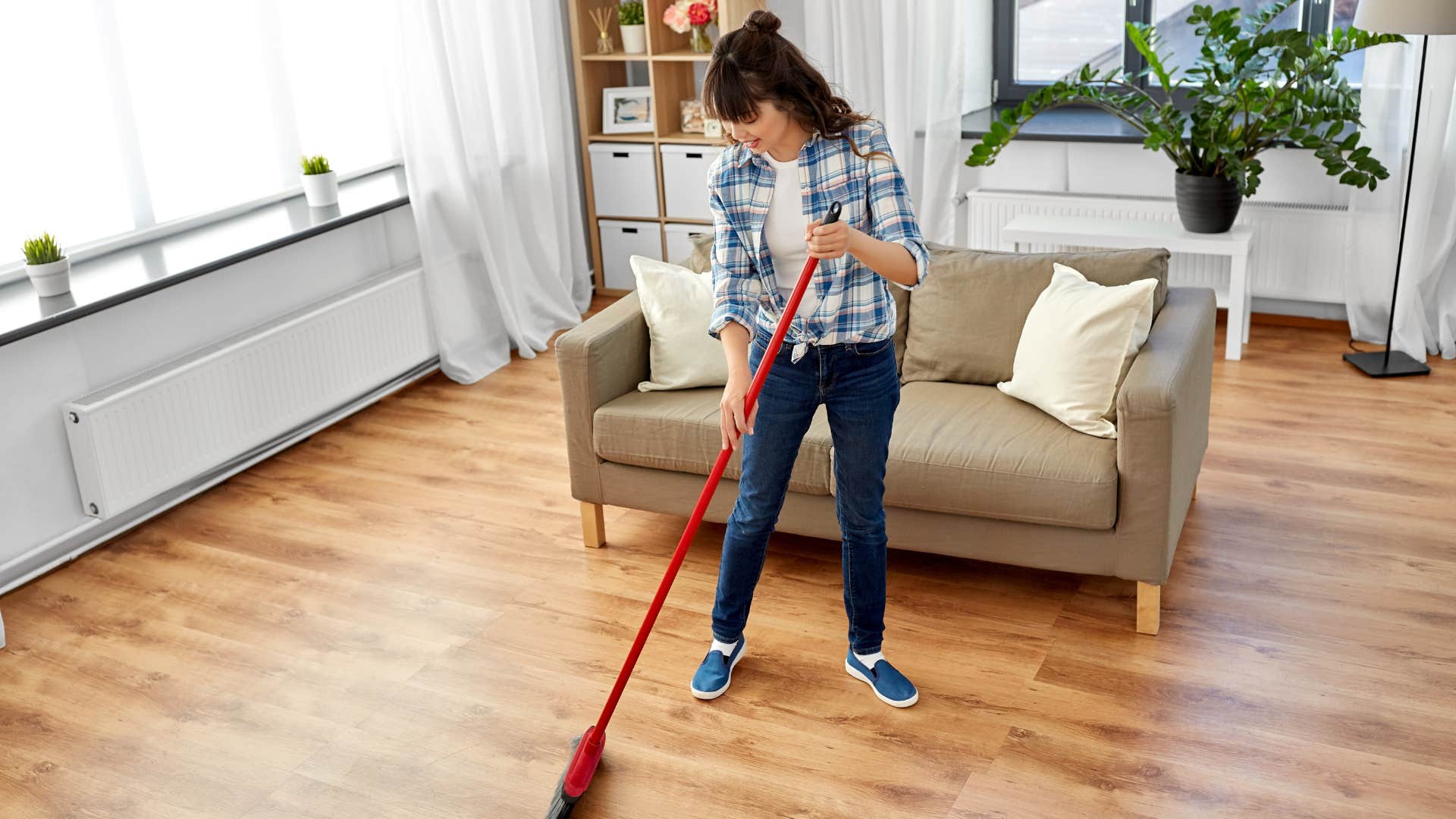 Woman using a broom and dustpan at home.