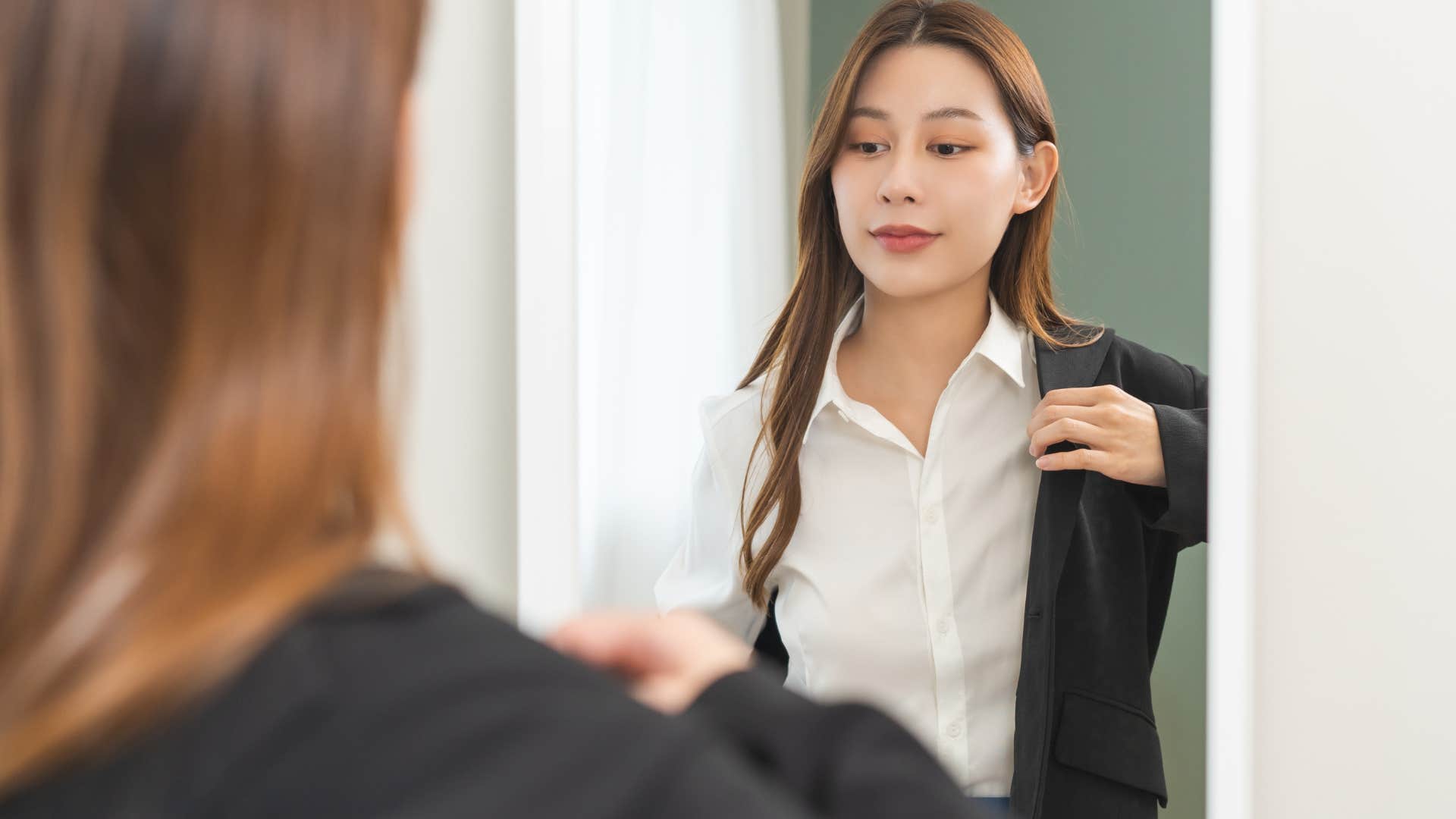 Woman getting dressed in high-quality clothes in the mirror.