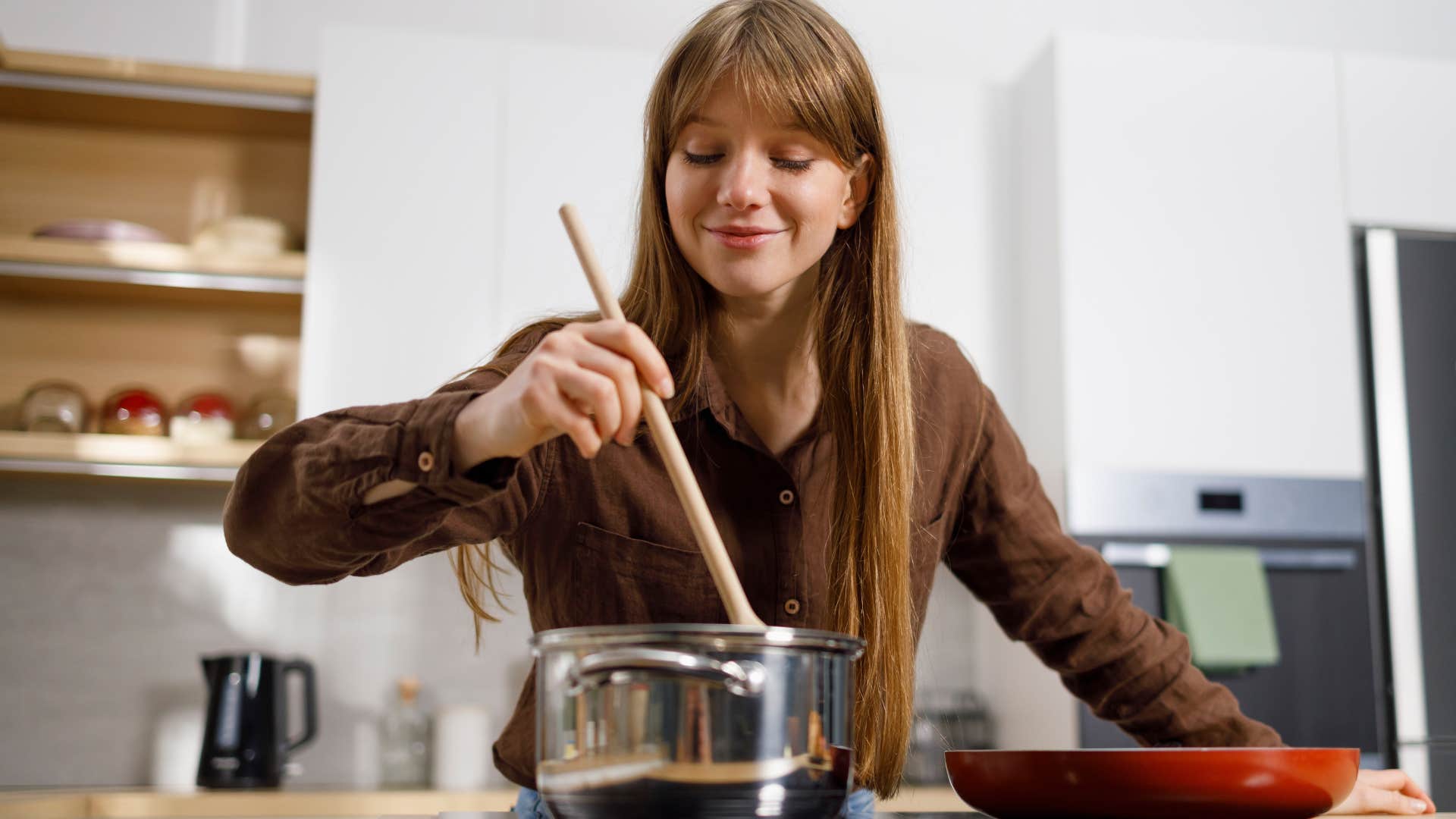 Woman cooking with high-quality pots and pans at home.