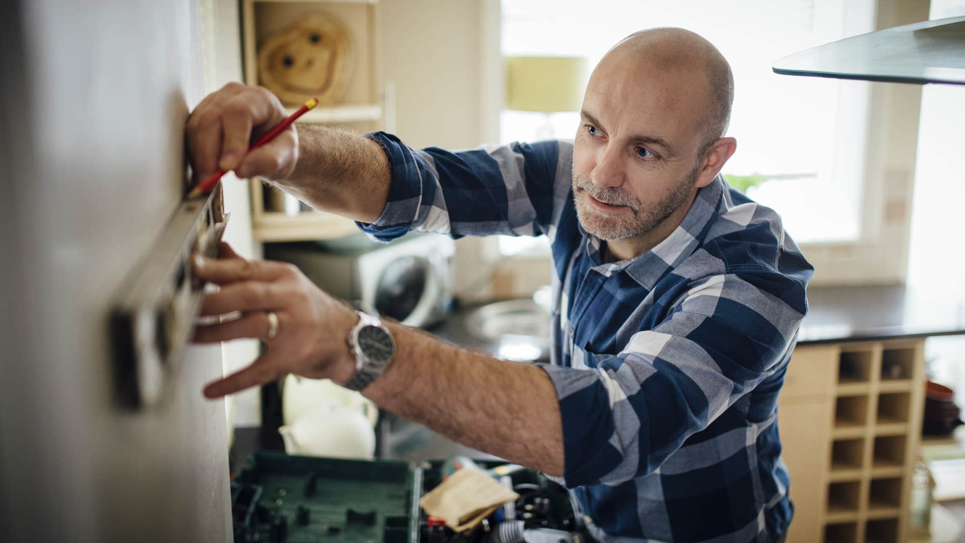 Man using a tool set to hang something on the wall.