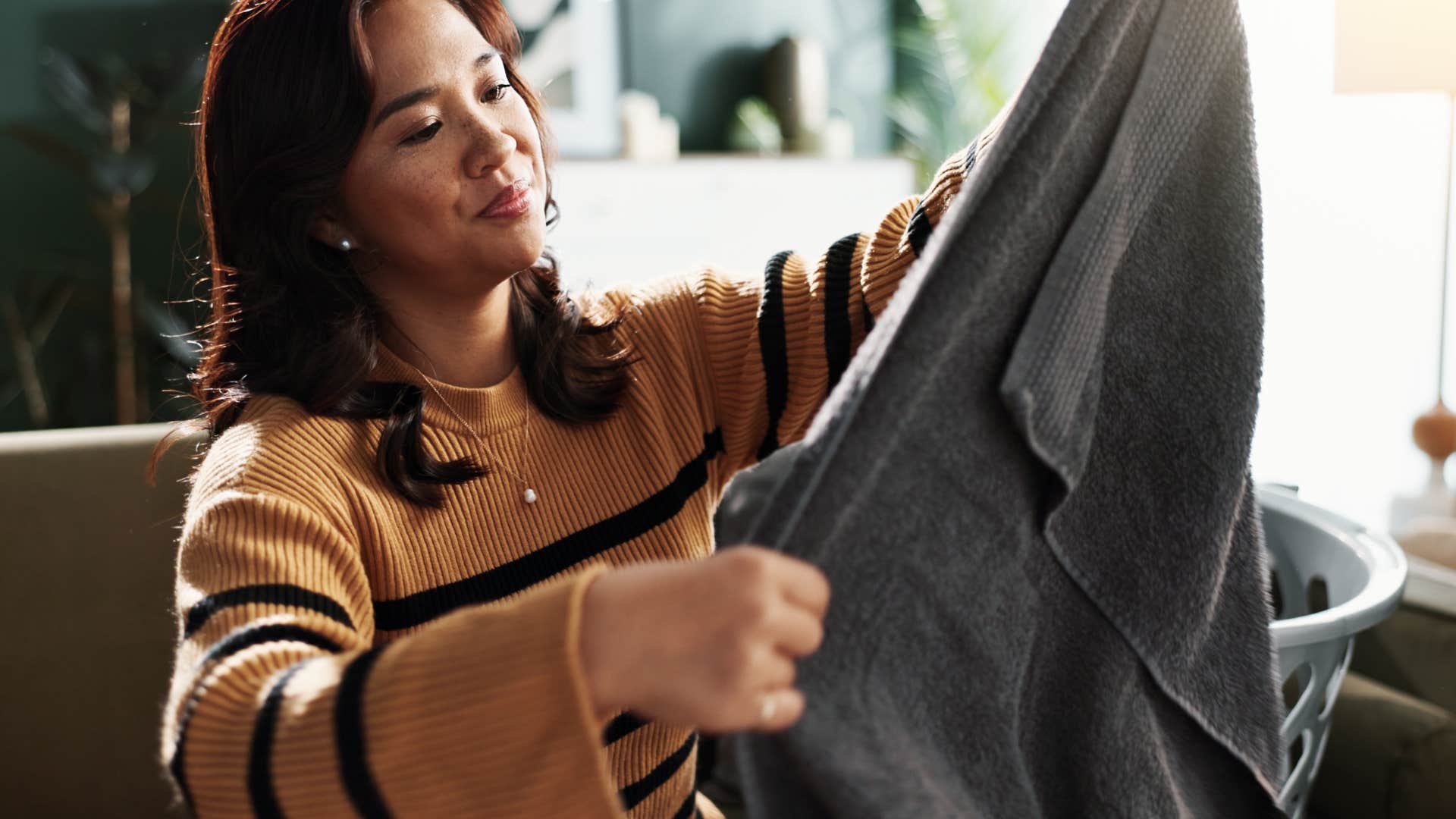 Woman folding towels and rags at home.