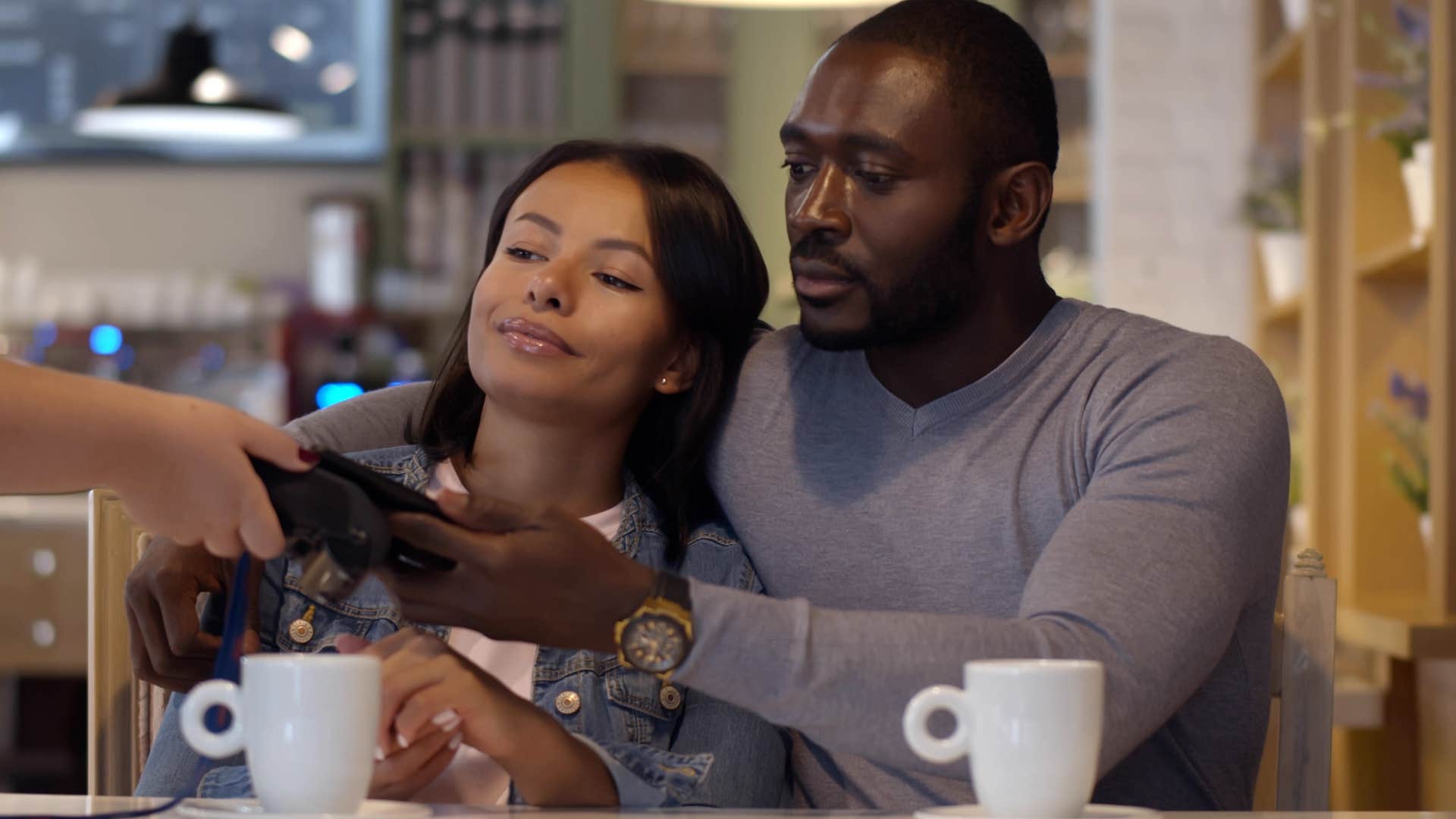 Man hugging his partner and splitting the bill at a restaurant.