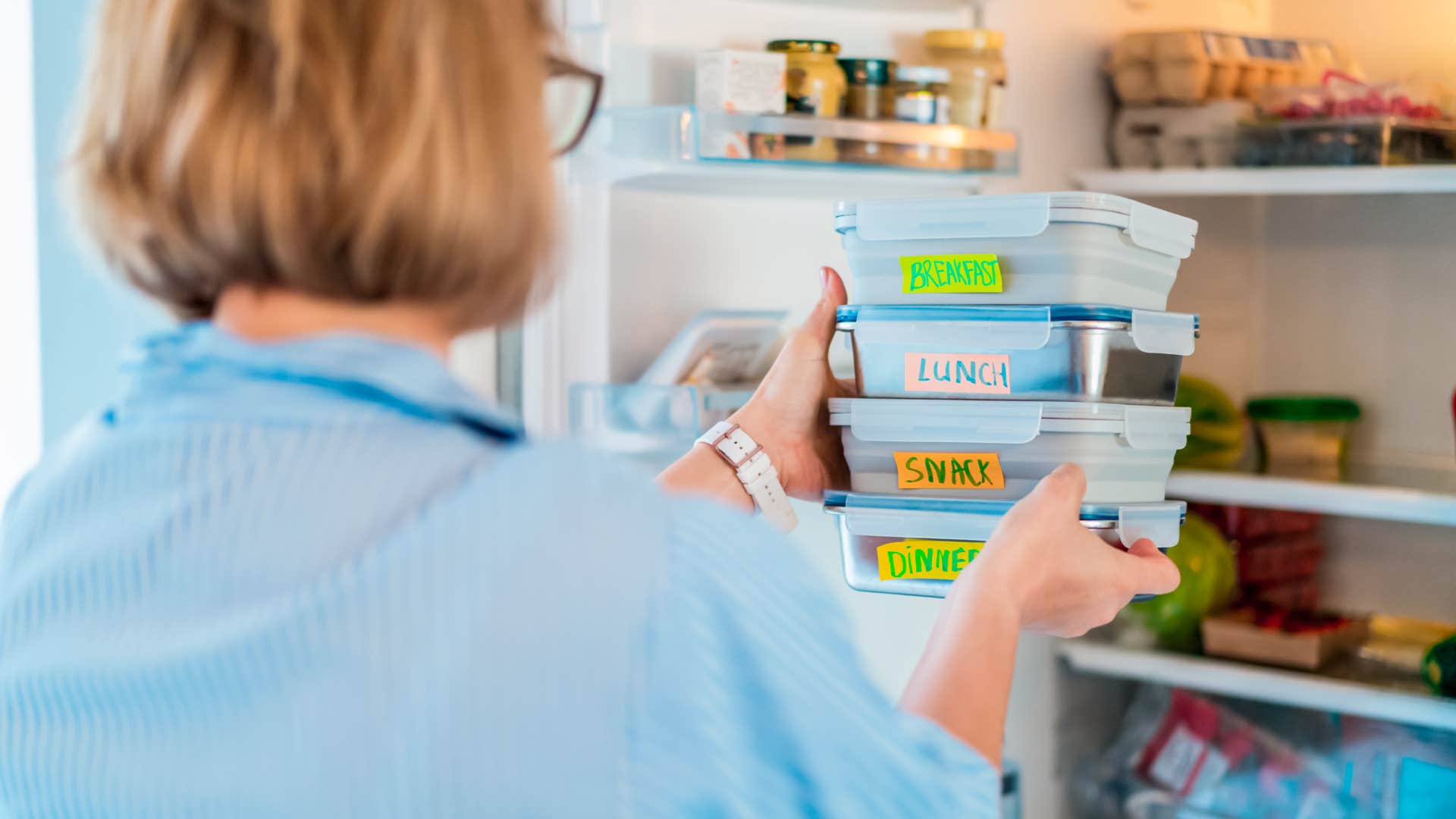 woman putting reusable Tupperware into her fridge