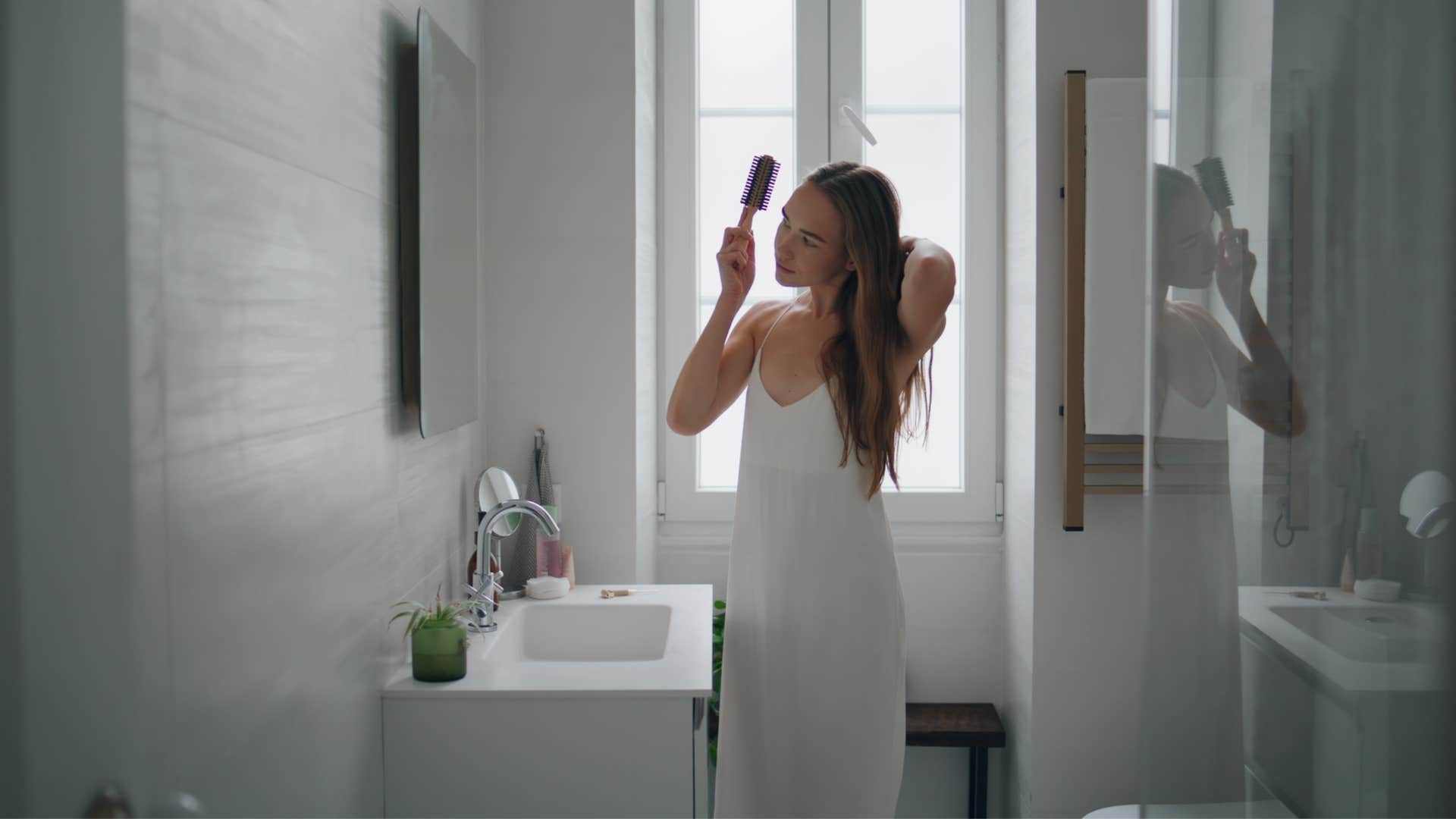 woman brushing her hair looking in the mirror
