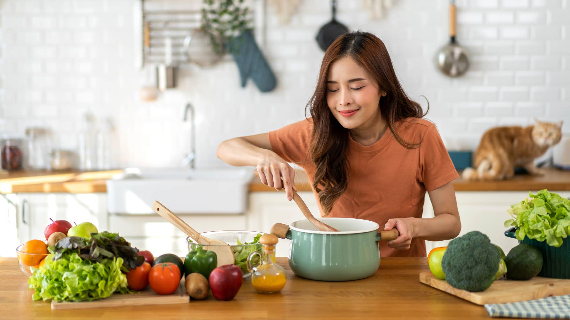 woman in tshirt cooking food instead of ordering out as she taste tests food