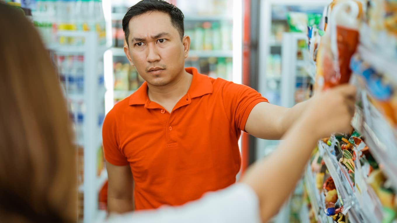 frugal man annoyed with womans purchase at grocery store