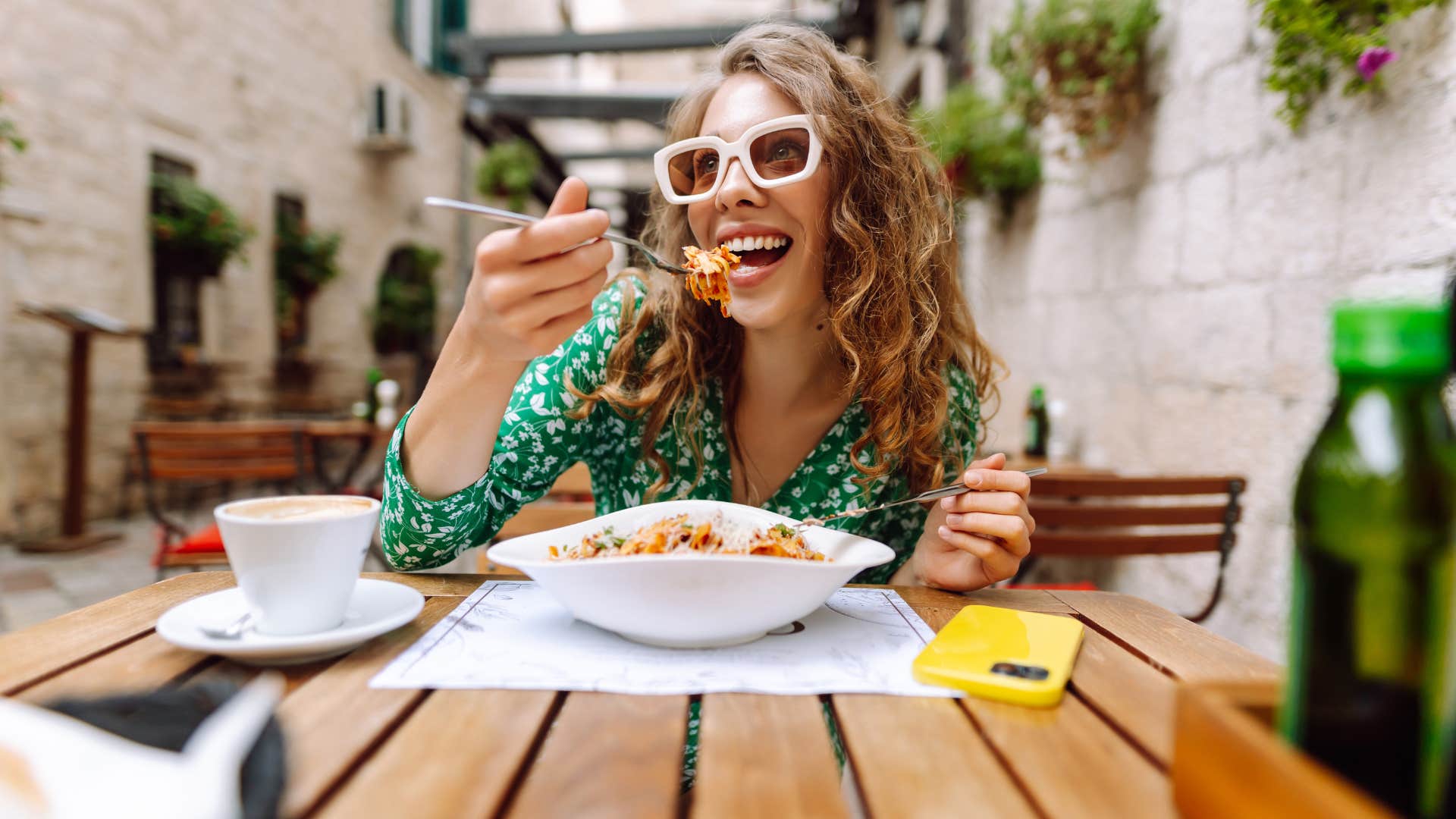 woman in green shirt dining out all the time as she eats food
