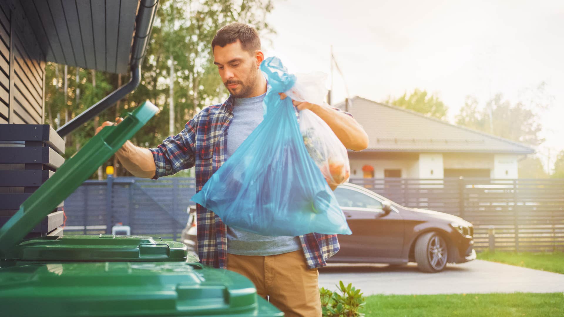man in plaid shirt throwing away reusable items in trash can
