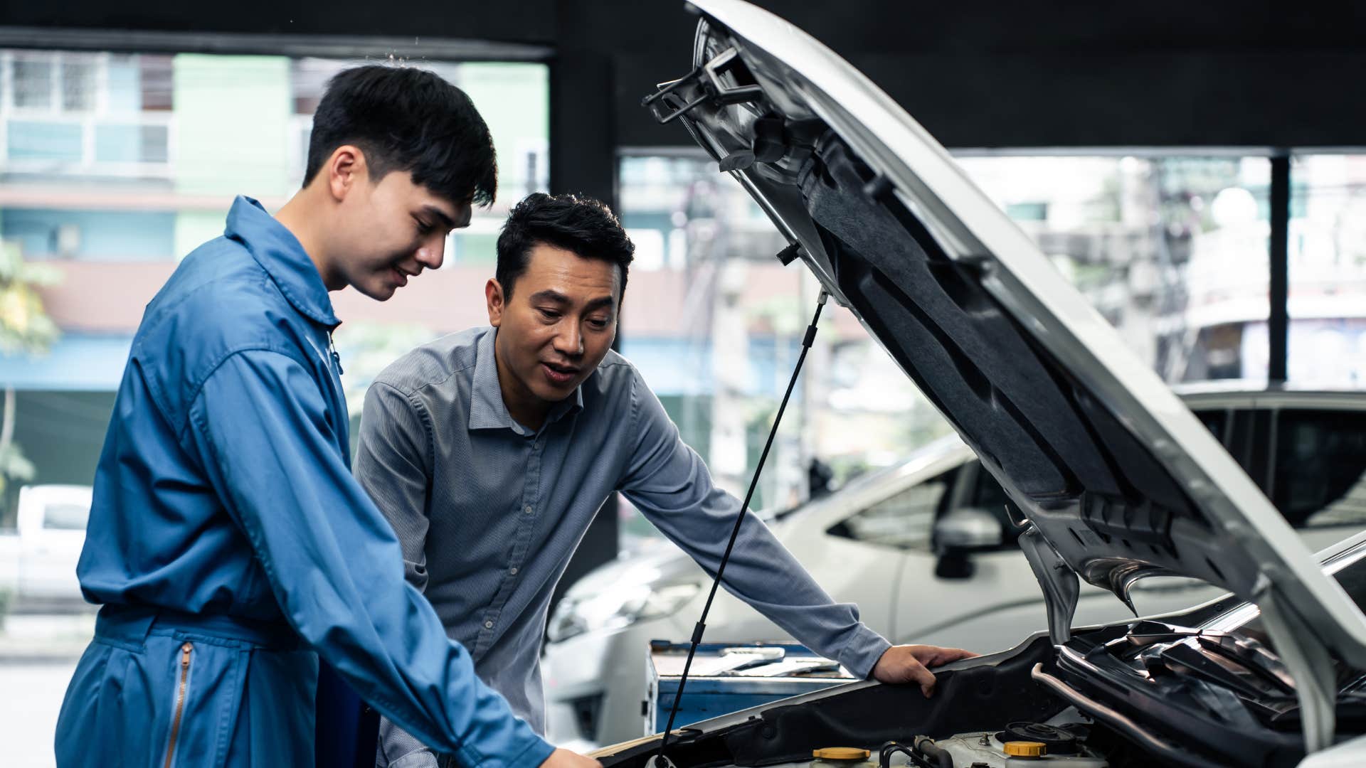 gen z man trying to perform car maintenance with mechanic