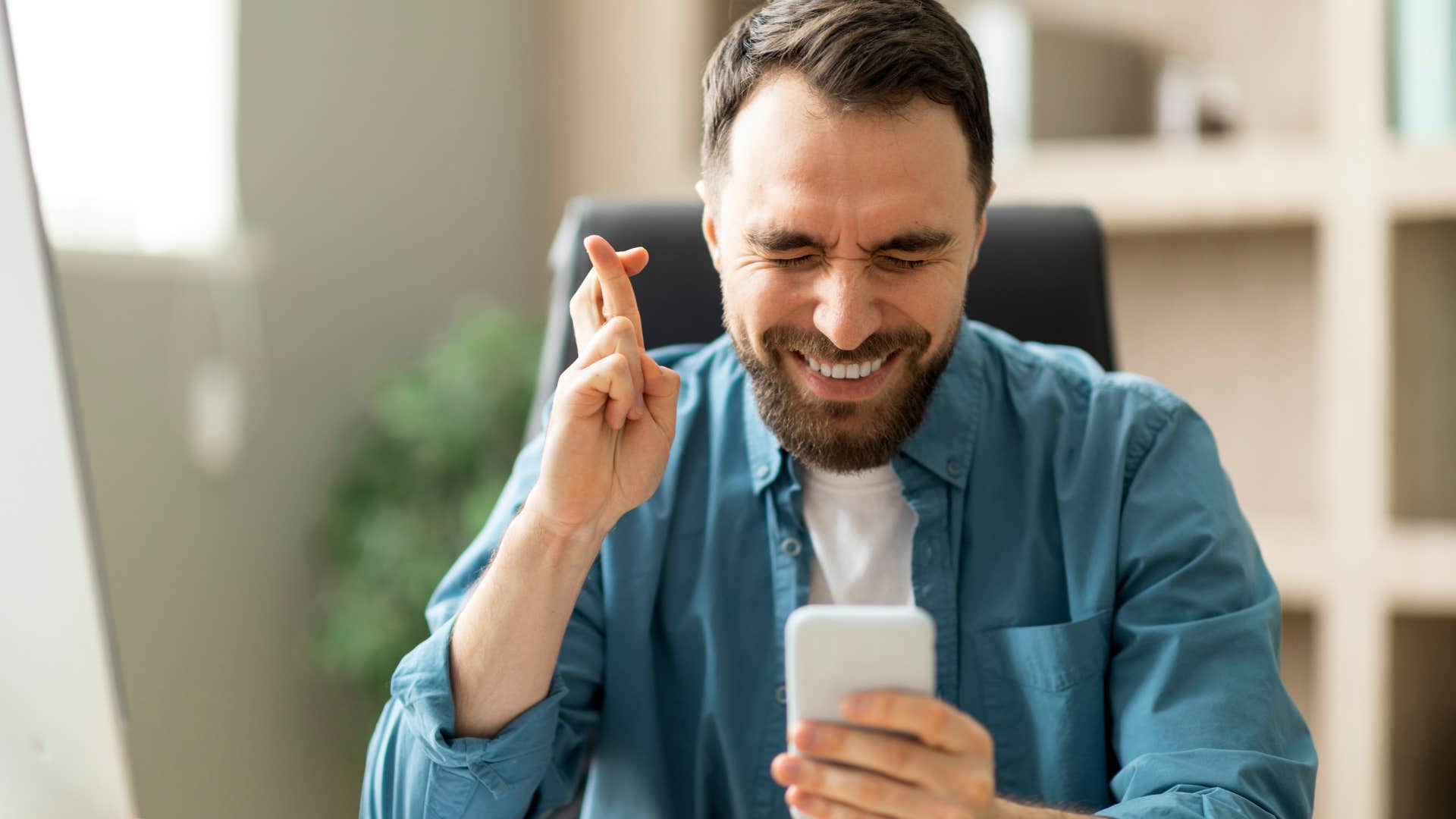 lazy man who relies on luck crossing his fingers looking at his phone