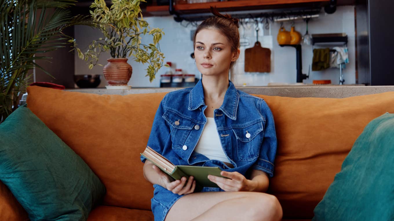 Things In Your Home That Block Your Financial Blessings, According To Feng Shui woman sitting in her living room blocking financial blessings