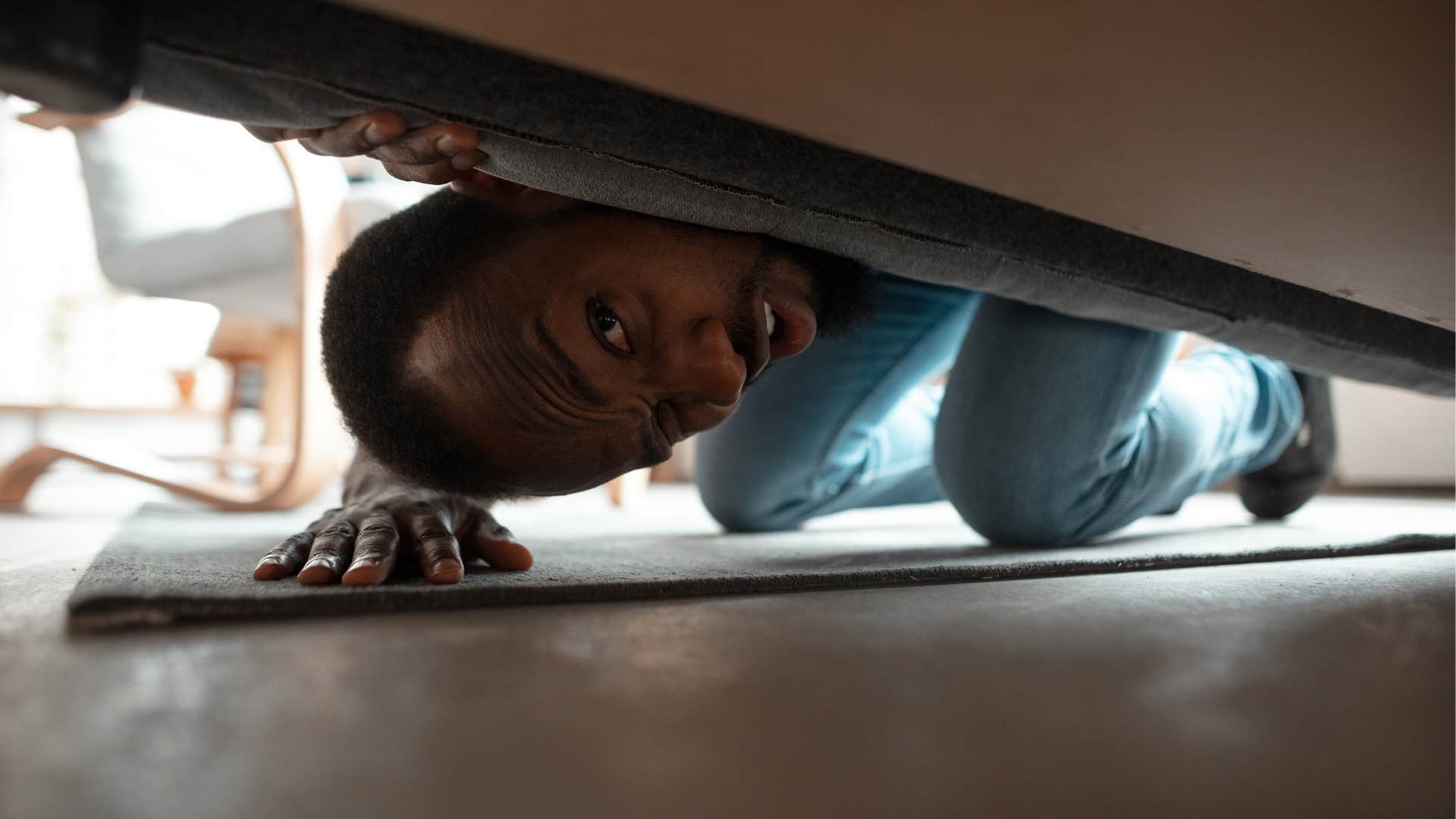 man looking under bed to clear storage